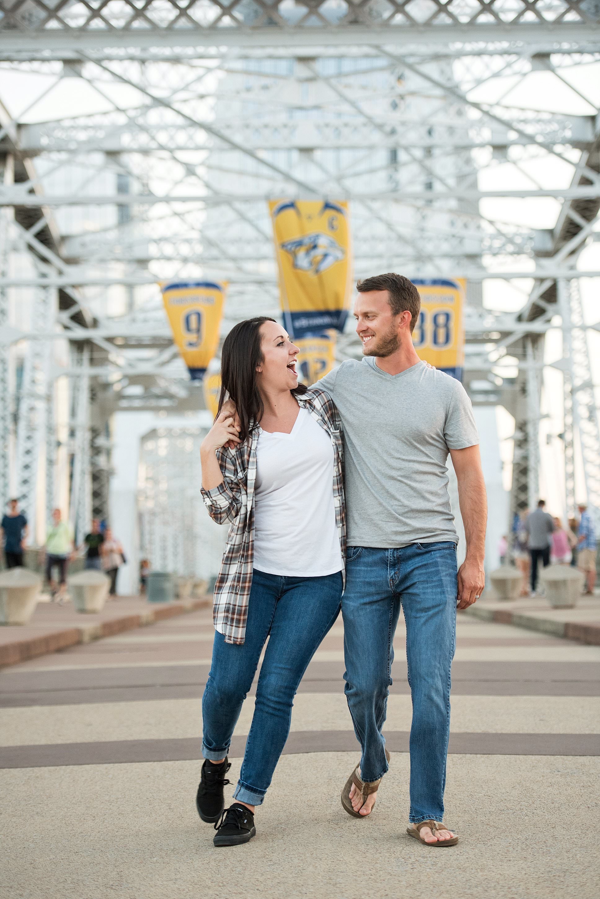 Couple strolling the pedestrian bridge in downtown Nashville with the Predators banners waving overhead