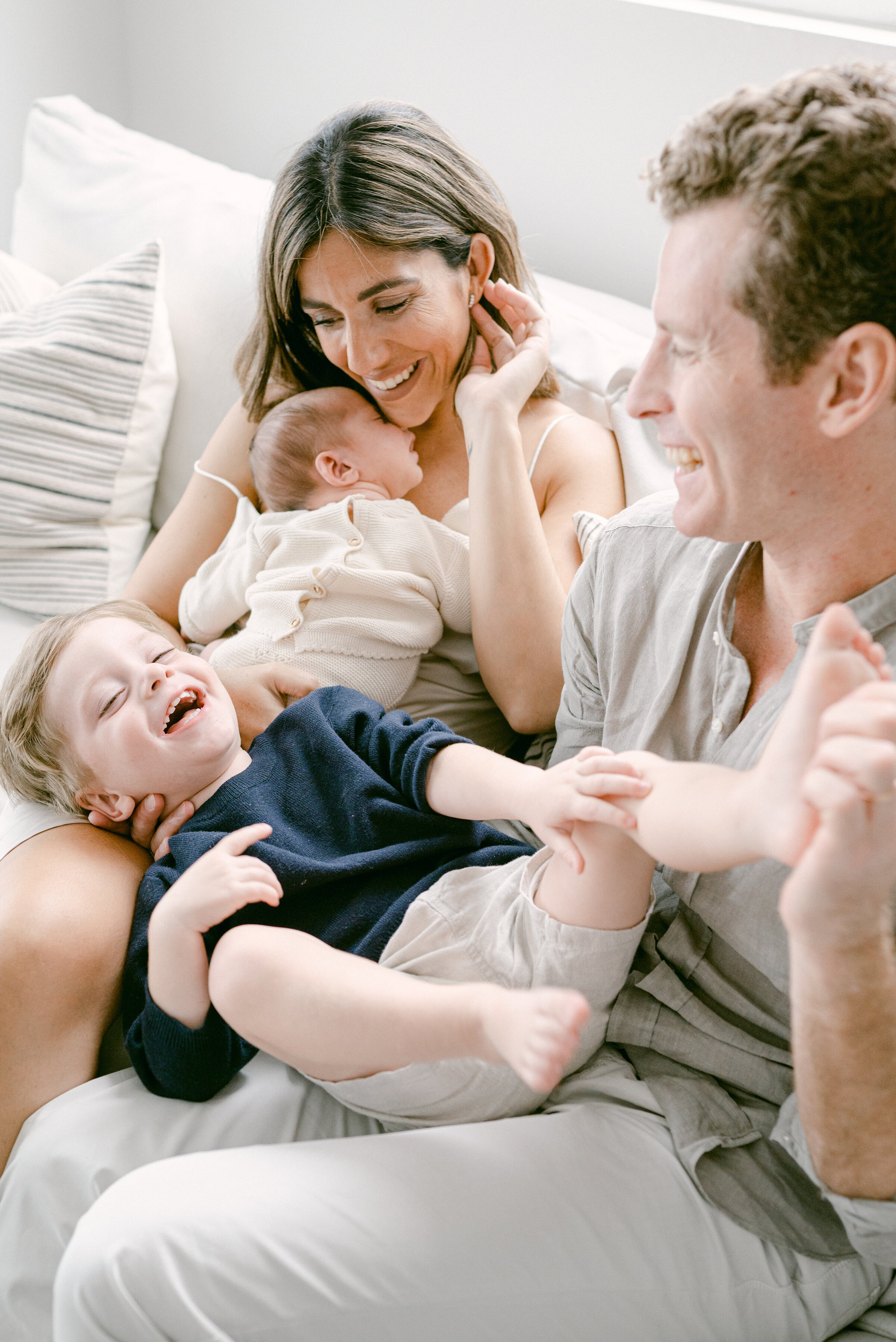 Family of 4 tickling on the couch by Miami Newborn Photographer