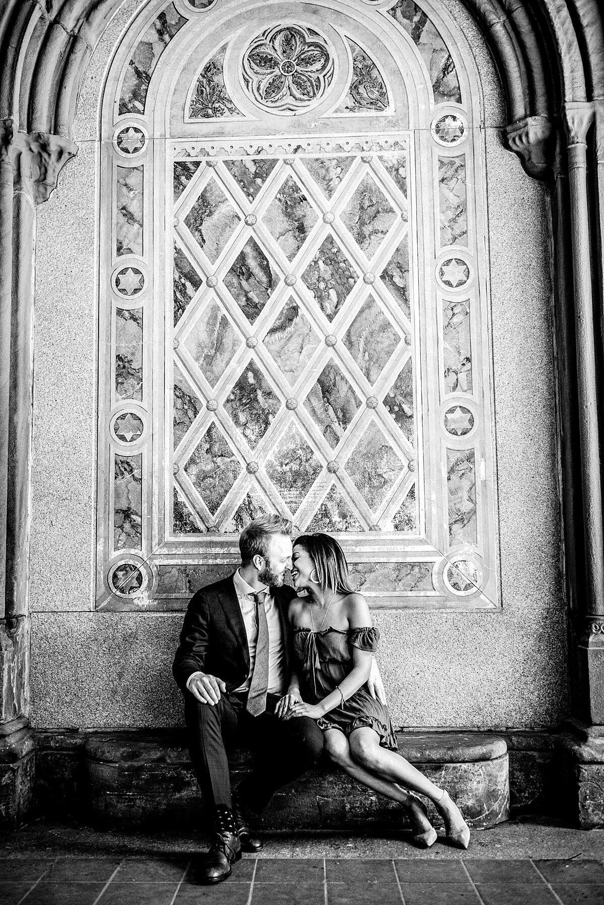 Black and White photo of couple sitting in iconic New York archway in Central Park