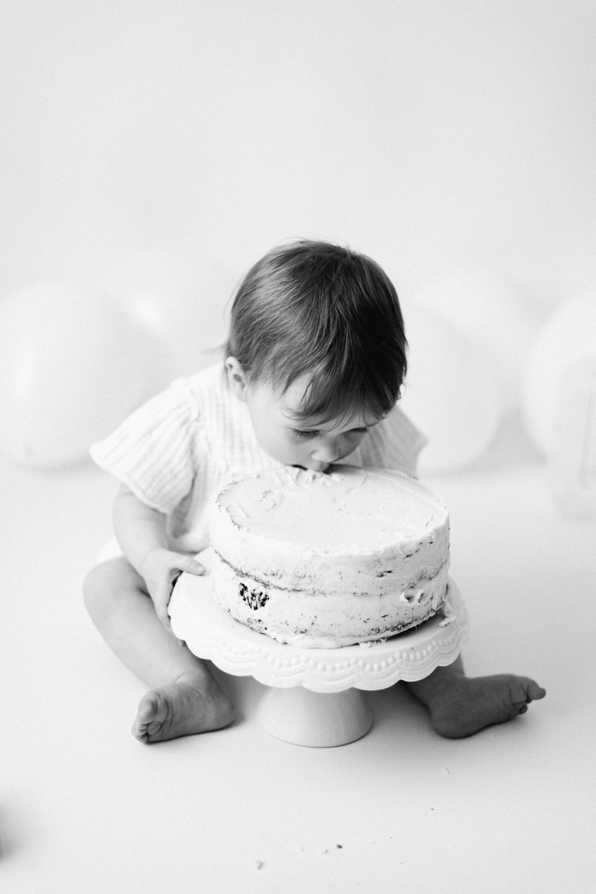 Little girl eating a cake with her face in the cake at cake smash photoshoot  in Billingshurst