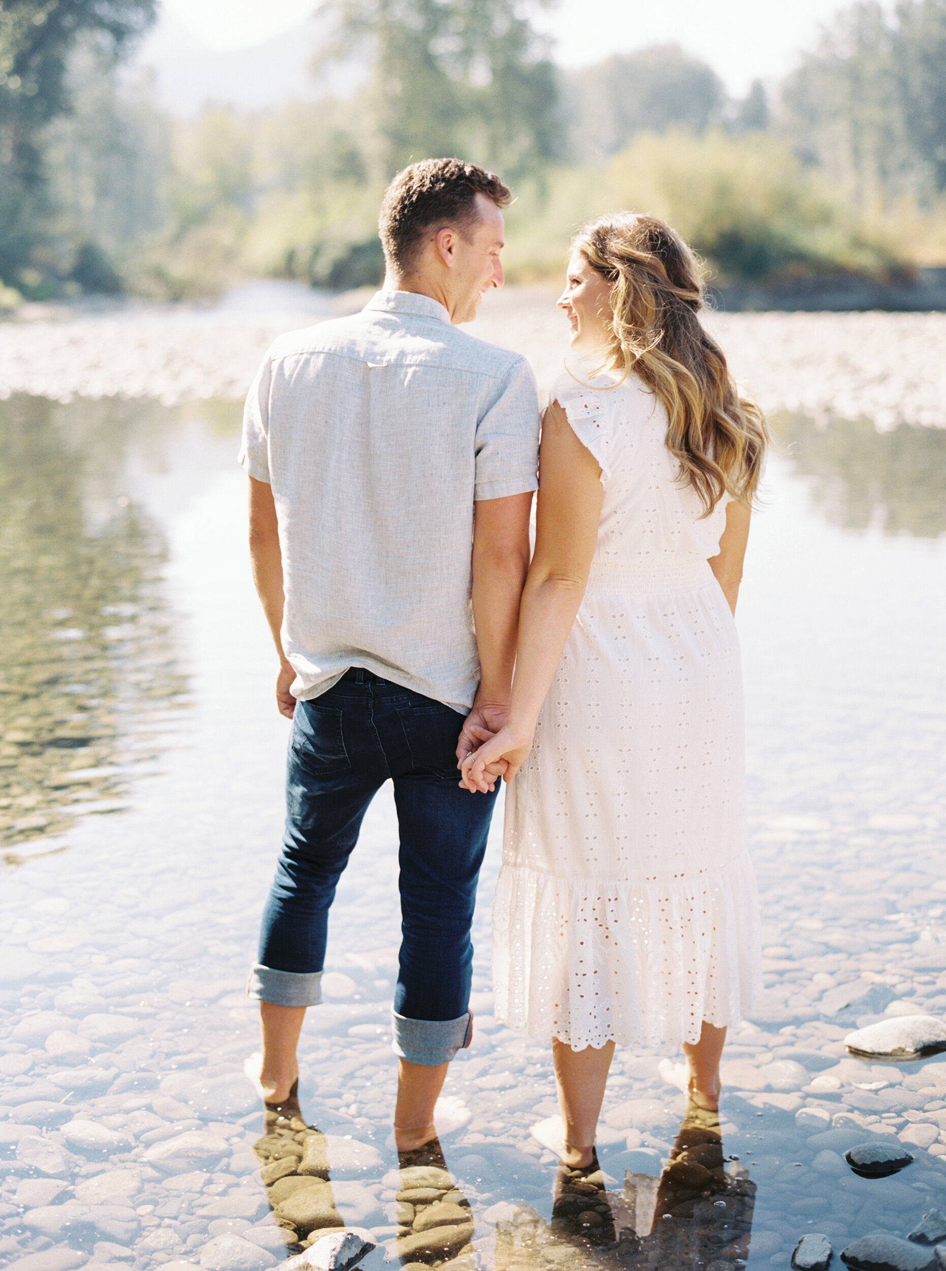 couple holding hands while standing in river