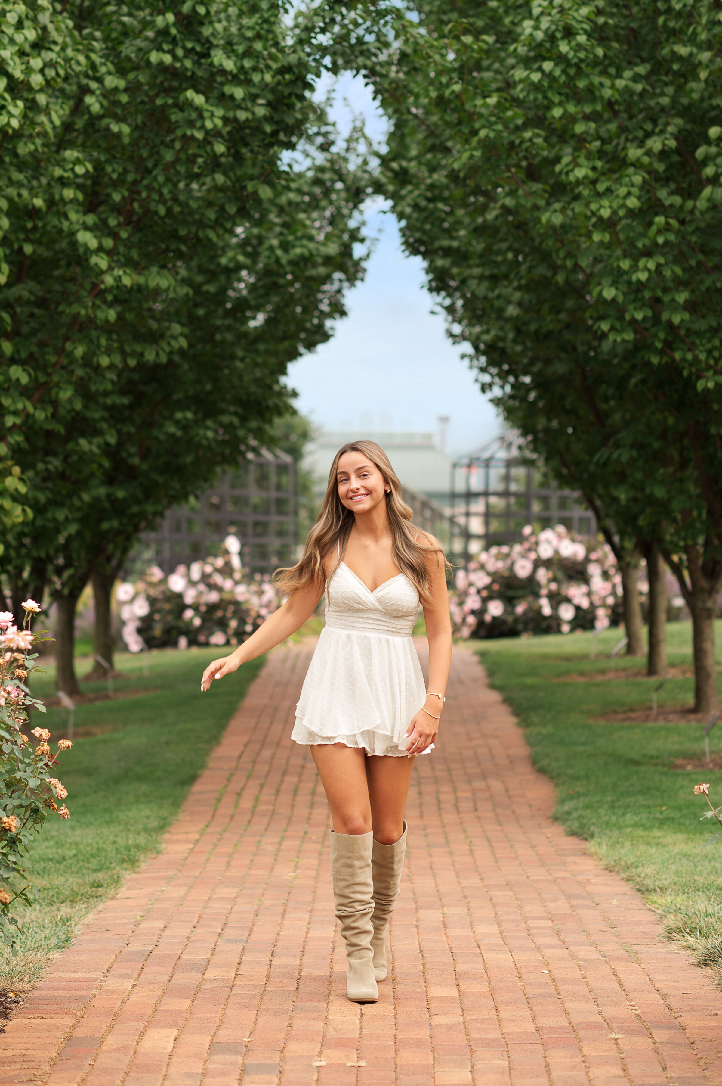 Senior girl walking on a brick path lined with trees at Hershey Gardens near York, Harrisburg, and Lancaster PA.