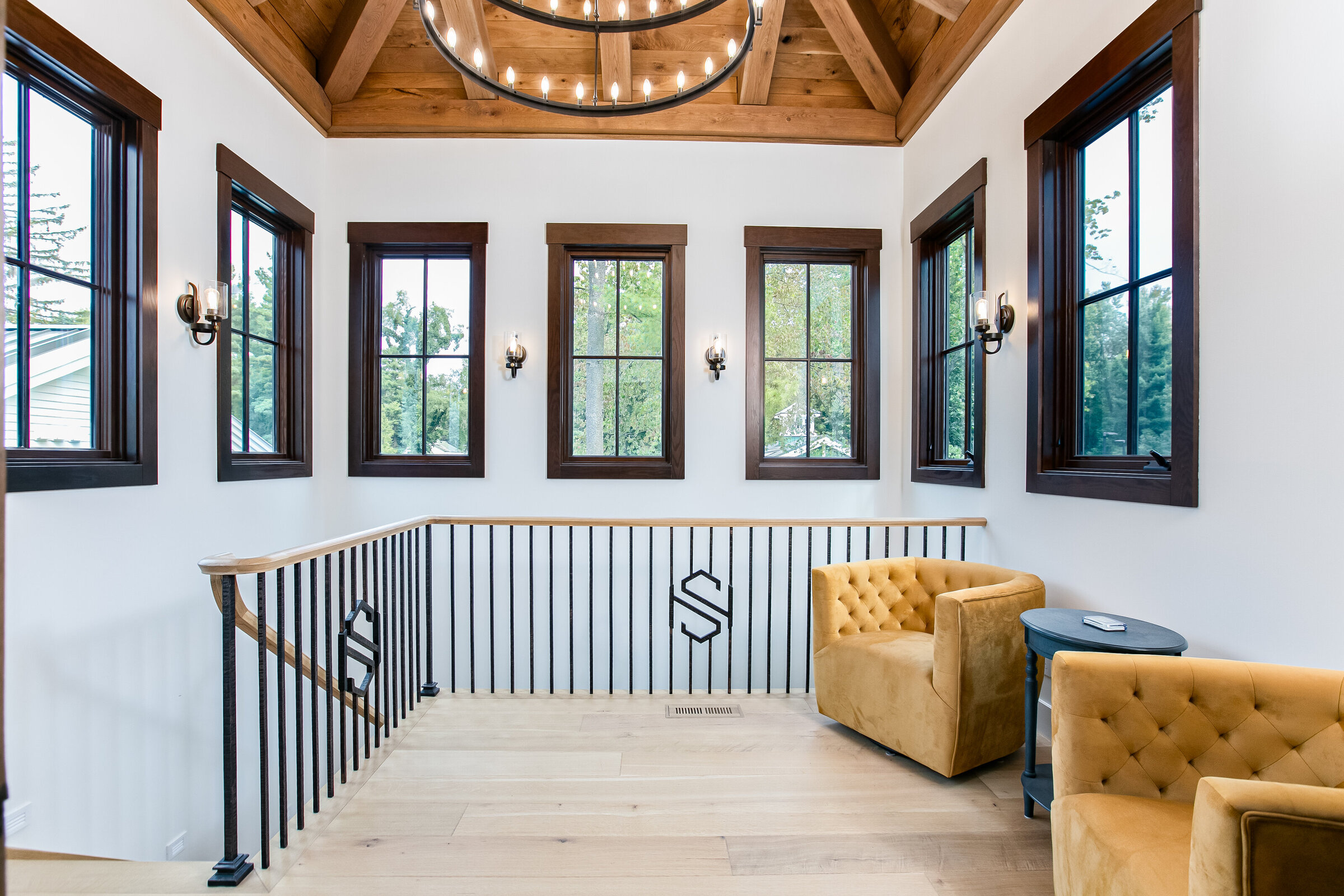 A stunning loft featuring panoramic windows with dark wood trim, white walls, and a grand chandelier. The design combines natural light with elegant details, creating a bright and sophisticated space with a modern touch.