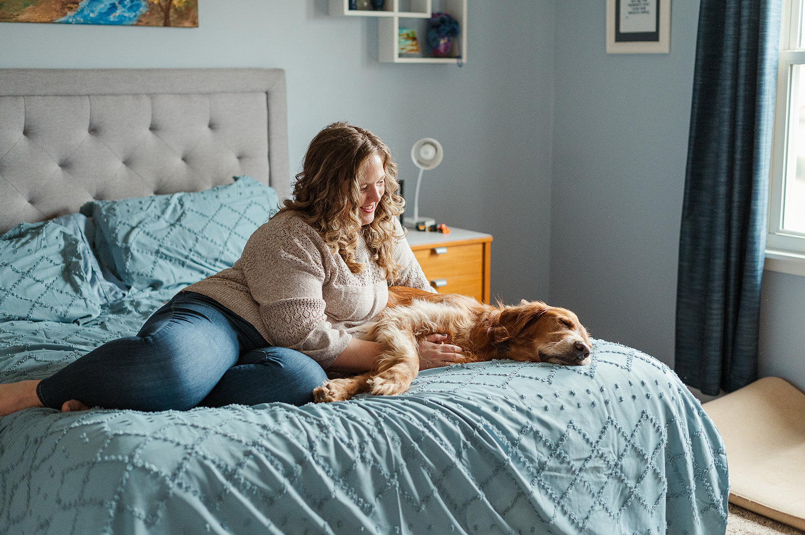 A mother sits with her toddler and golden retriever on the bed during a cozy lifestyle photo session in Lancaster County, PA.