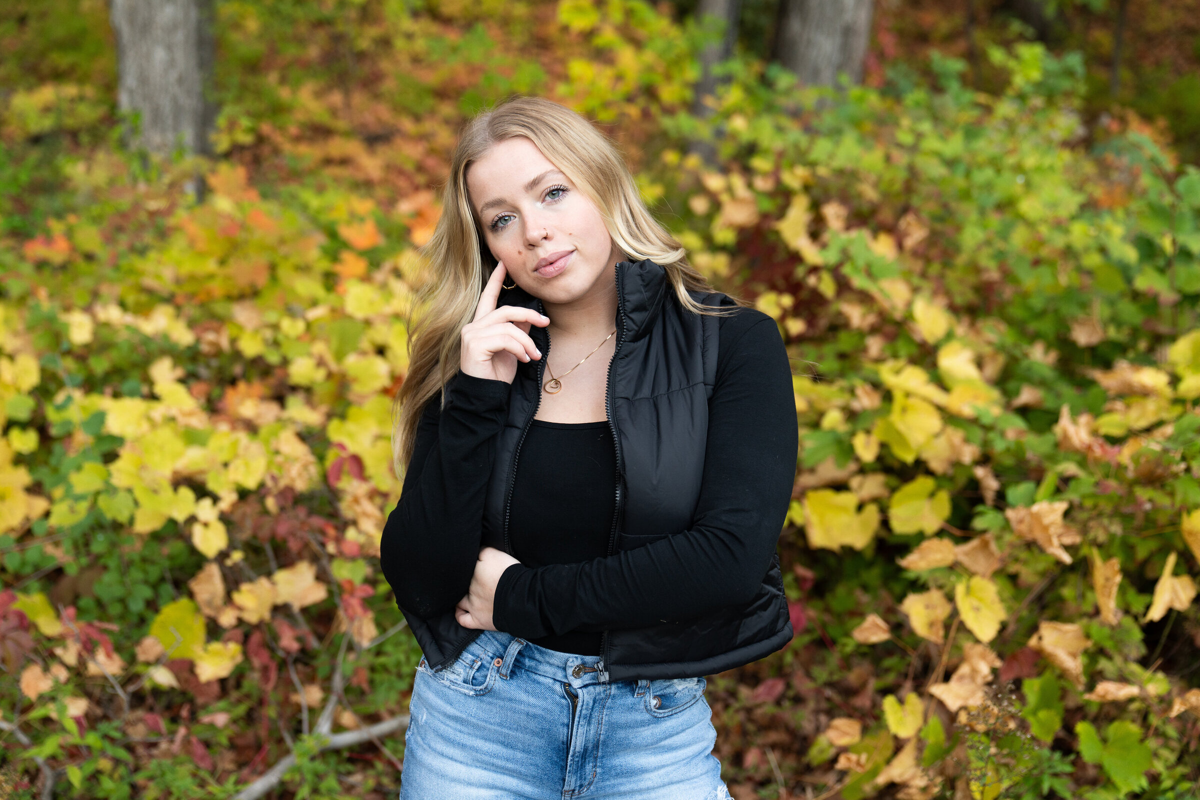 High school girl stands near fall color for her senior photos