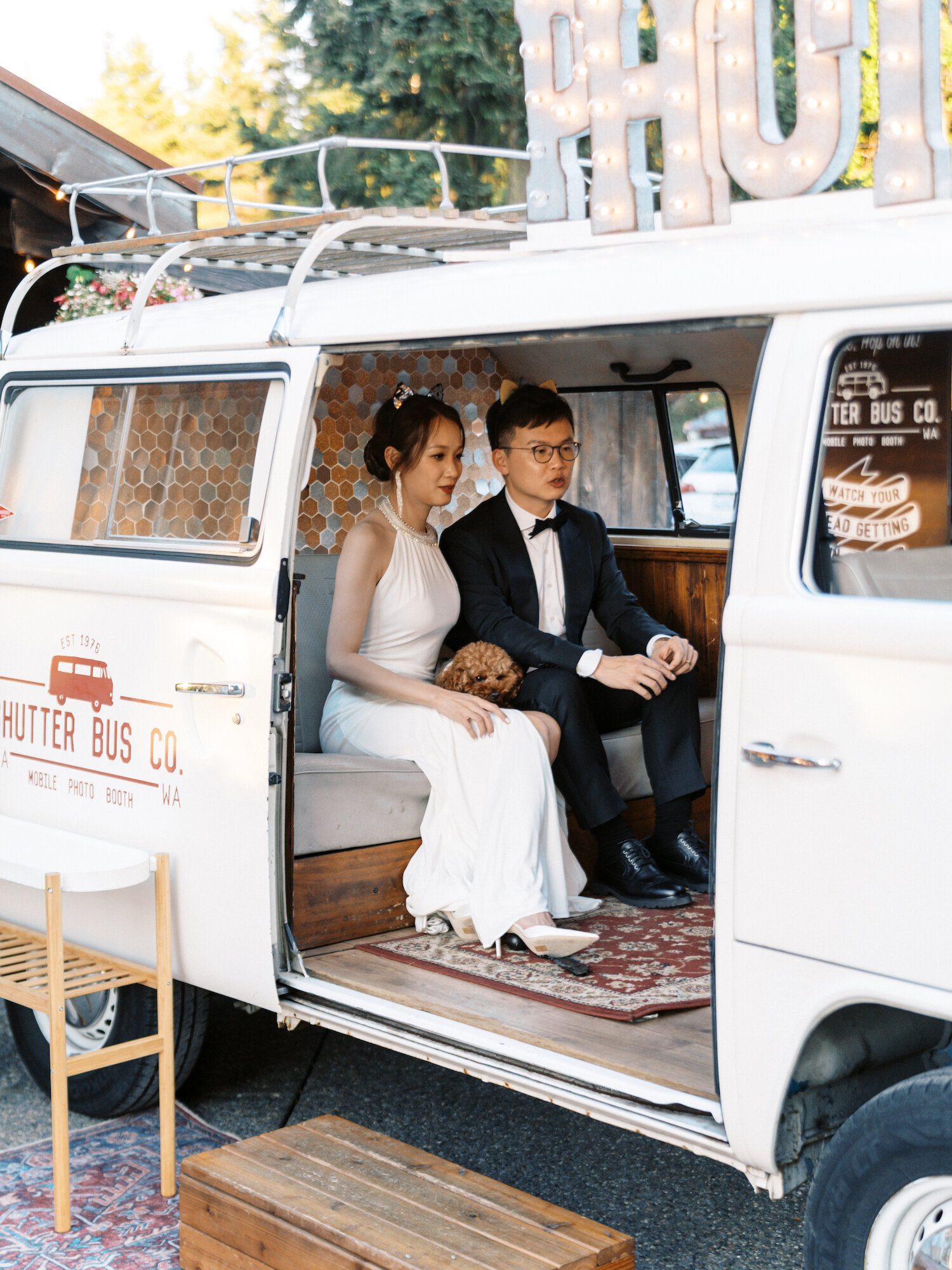 bride and groom sitting inside white photo booth bus