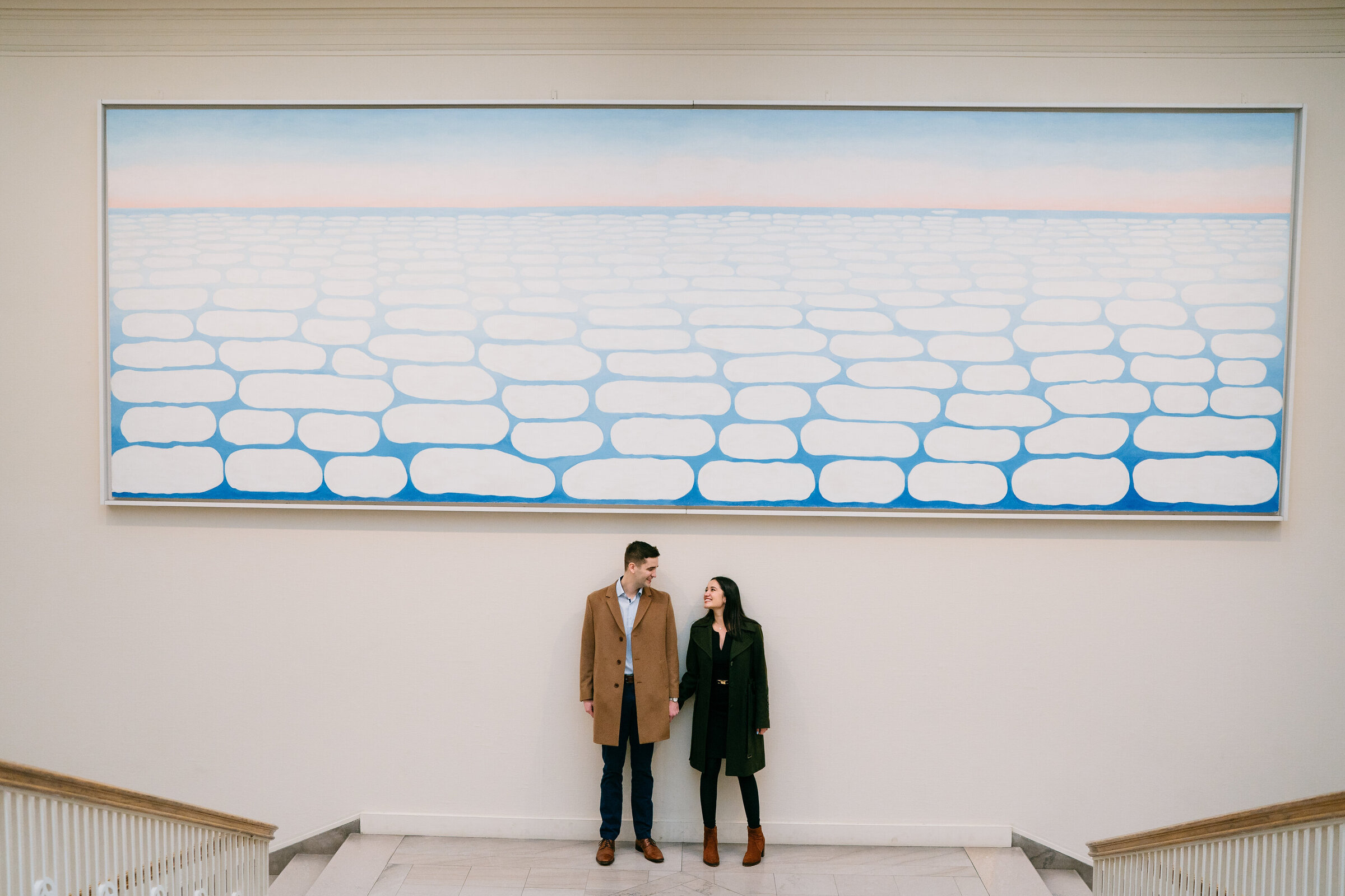 Couple holds hands below painting at the Art Institute of Chicago in engagement photoshoot