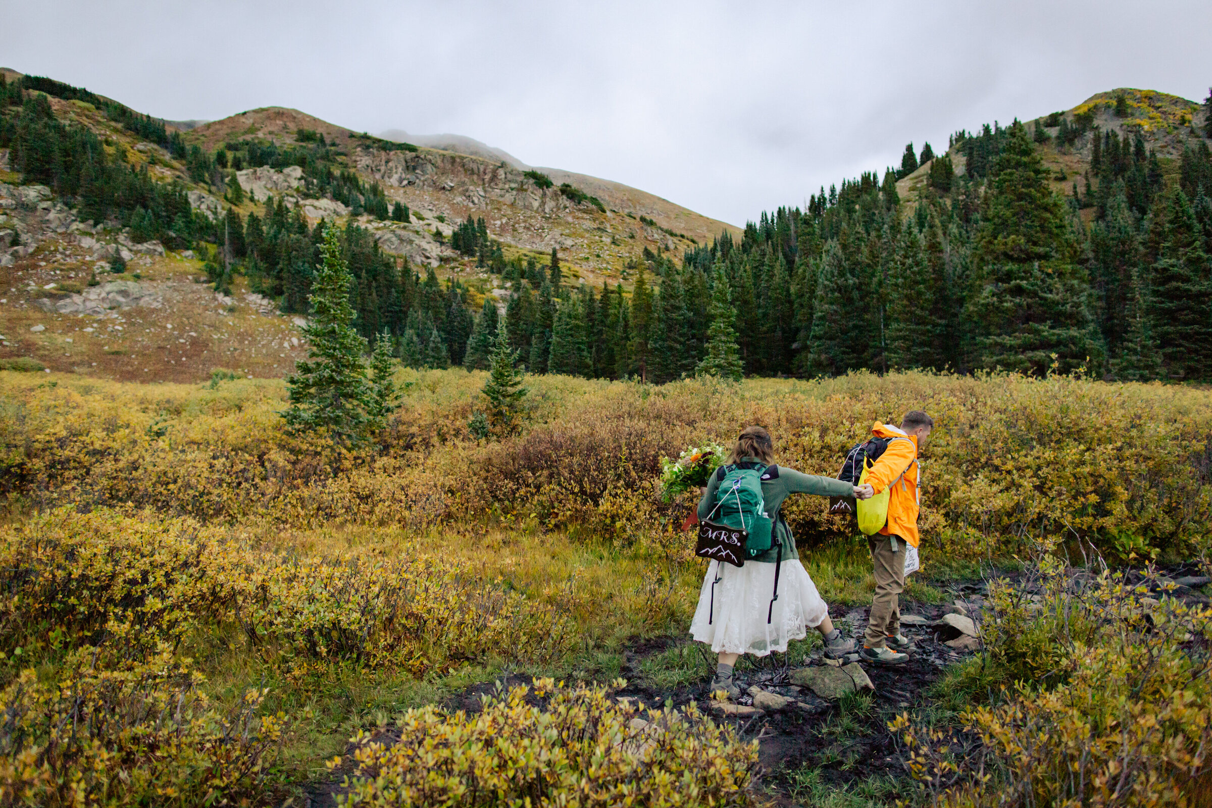 Groom leads bride down a hiking trail after their wedding ceremony