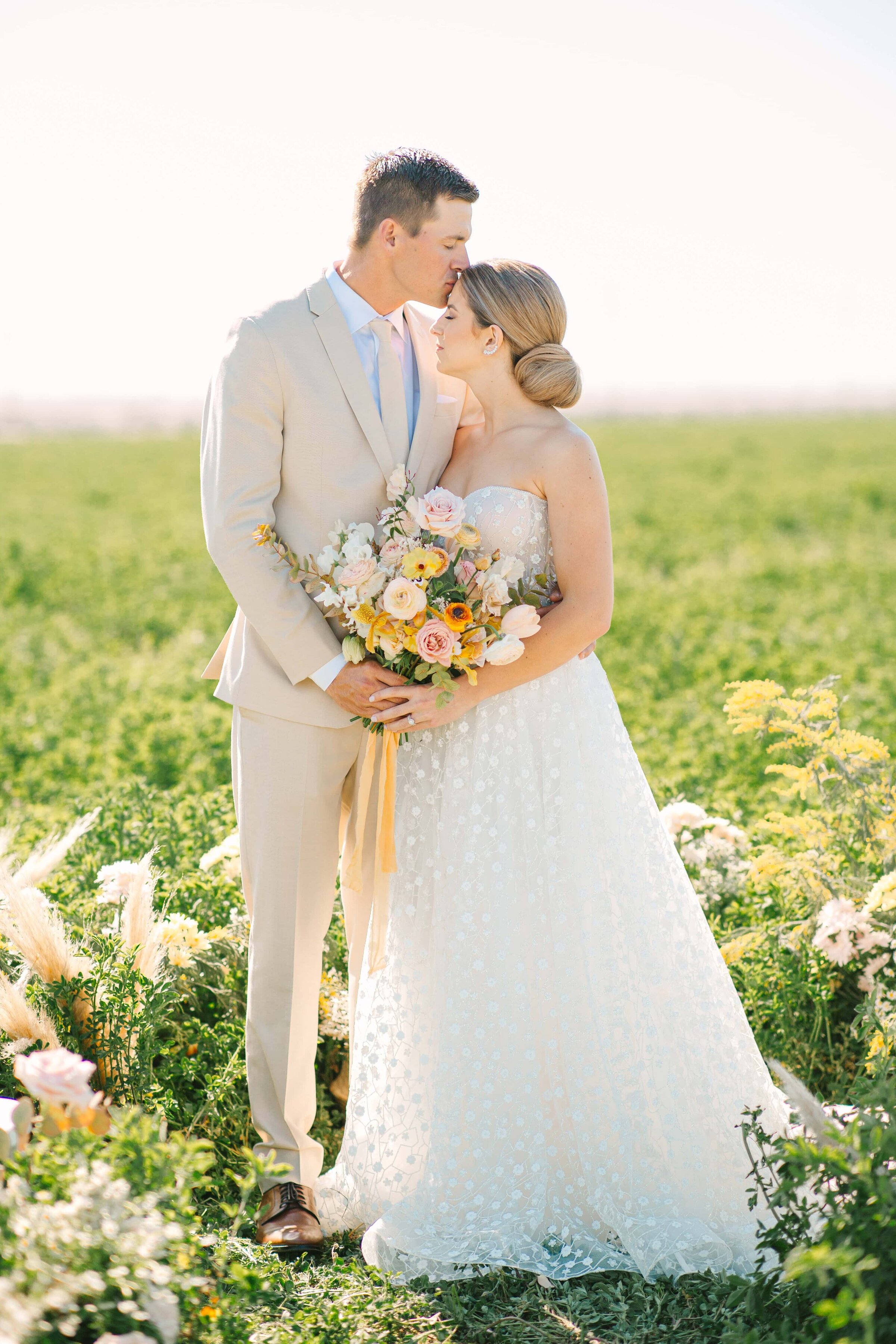 bride in a white gown and groom in a khaki suit in the middle of a field of flowers during their ceremony
