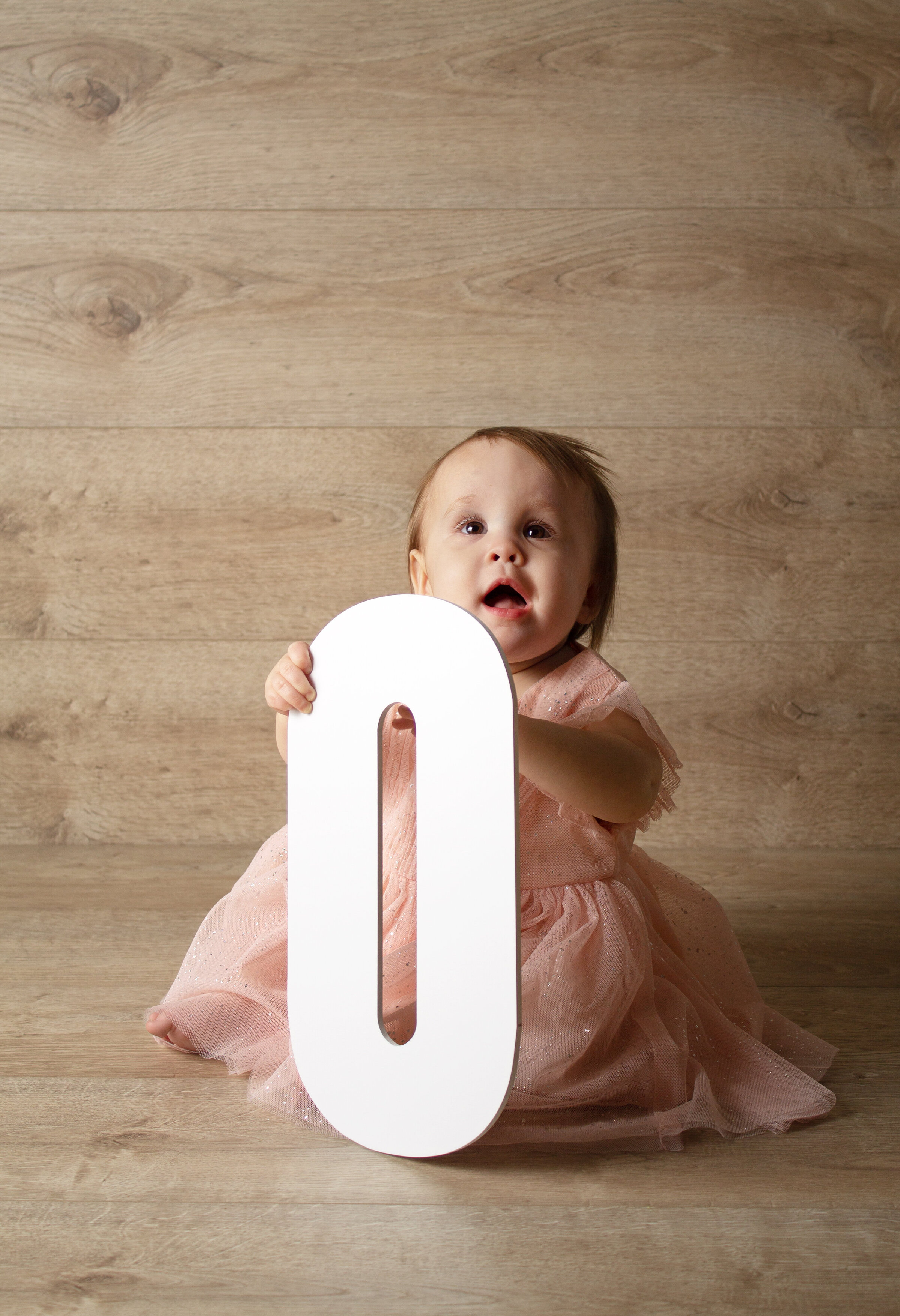 Cake smash session  with Willow holding the letter O.