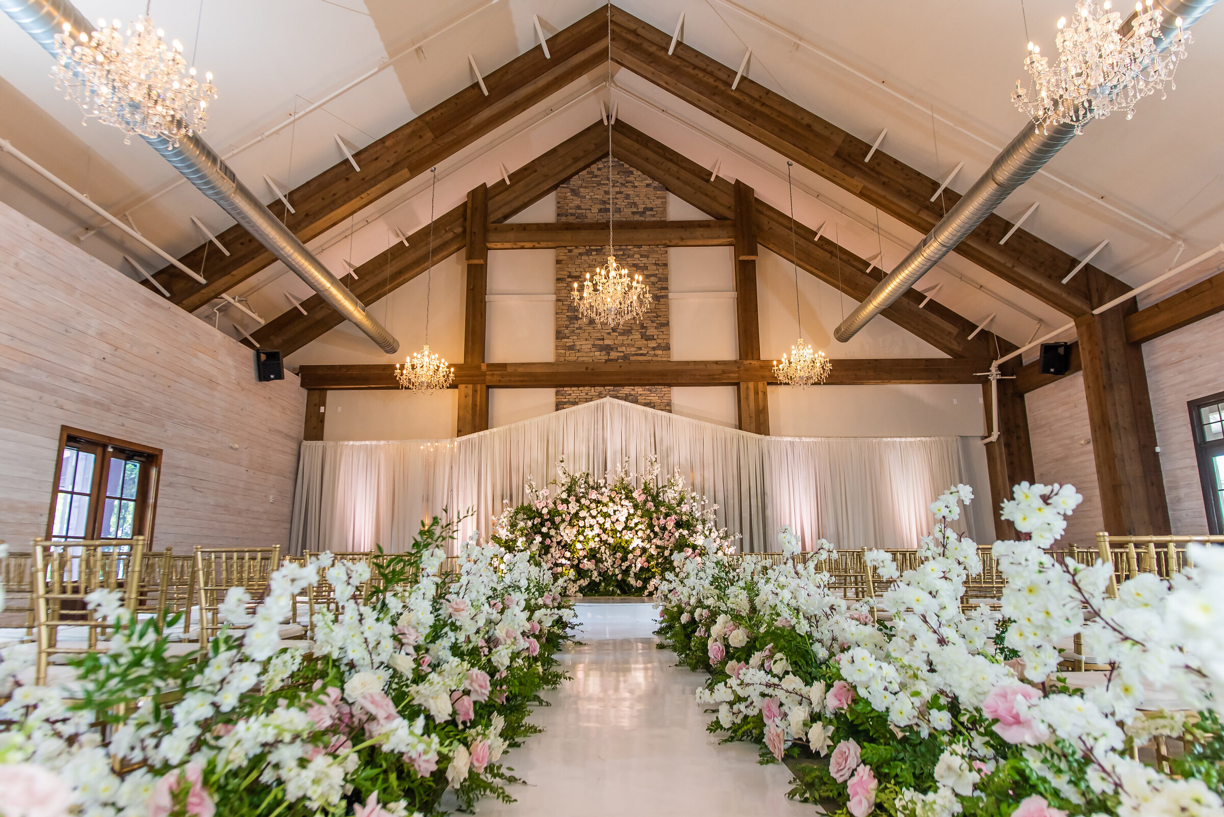 Romantic floral aisle with pink, blush, and white garden-style arrangements leading to a luxurious altar, captured at a Birmingham wedding by Wells Design Co