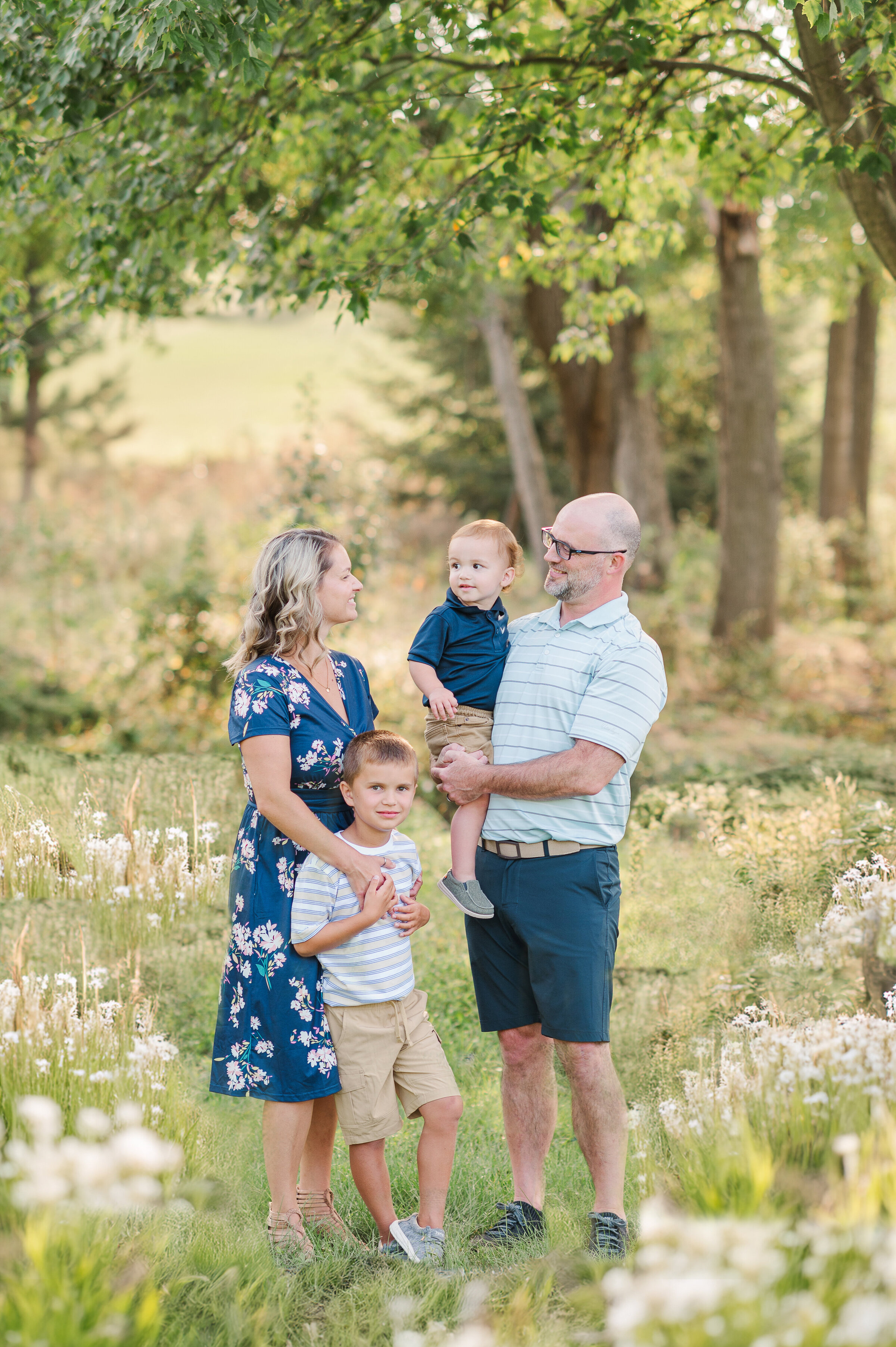family of four standing in tall grasses with white flowers by harrisburg pa photographer