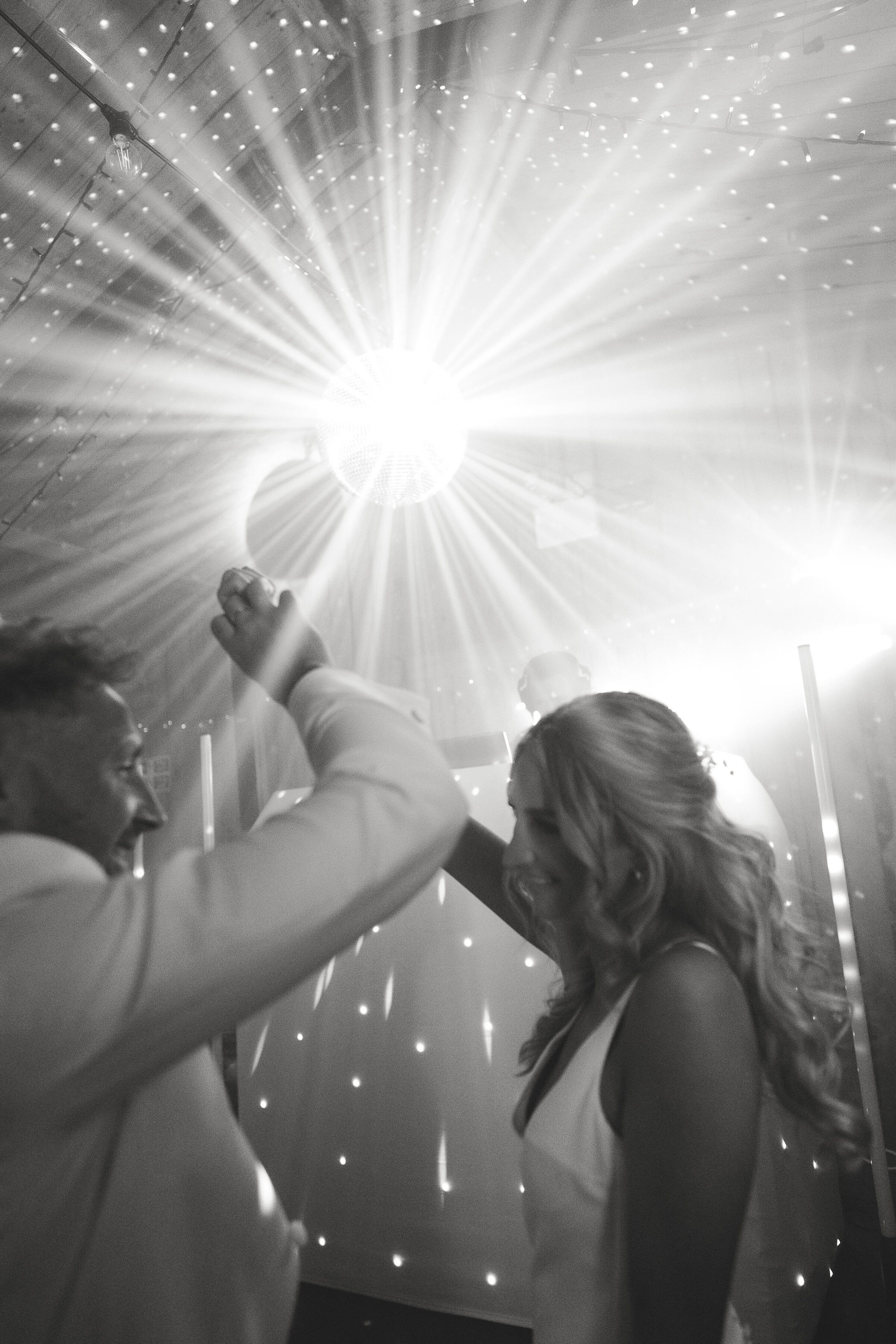 bride and groom dancing on wedding day under disco ball 