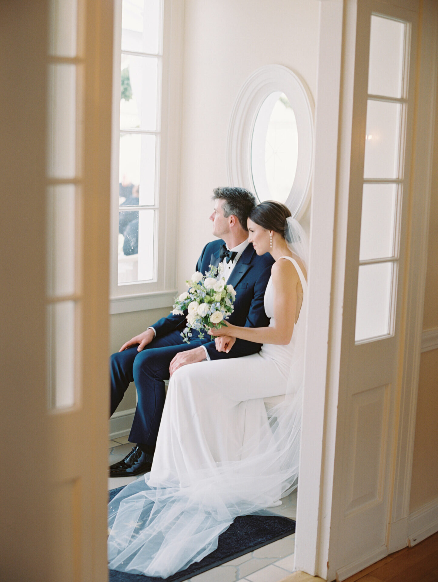 bride and groom sitting in natural light room full of windows