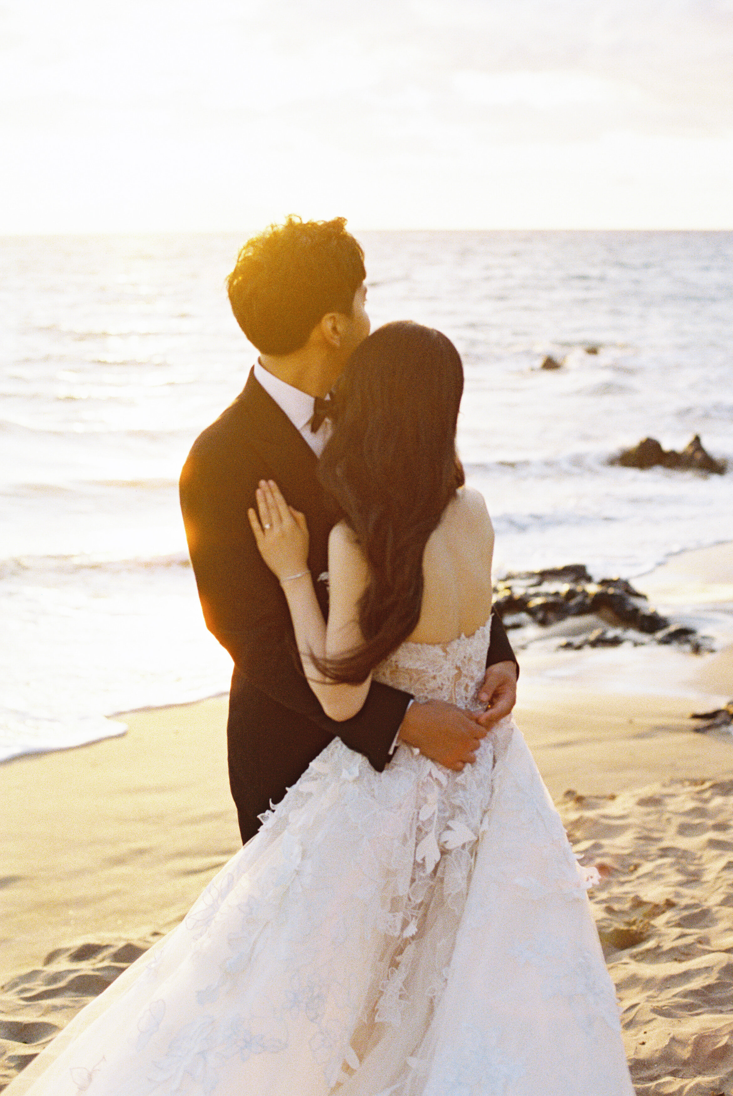 Wedding and Elopement Photographer, bride and groom standing in the sand, looking out over the ocean