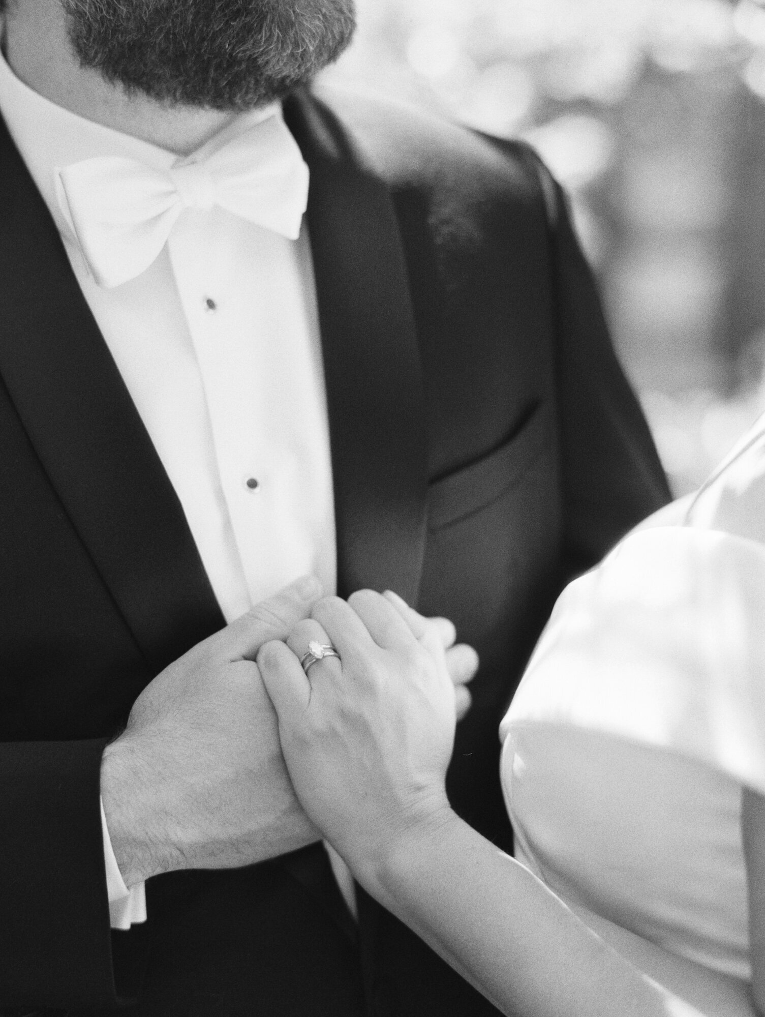 classic black and white film photo of a bride and grooms hands up close showing diamond ring