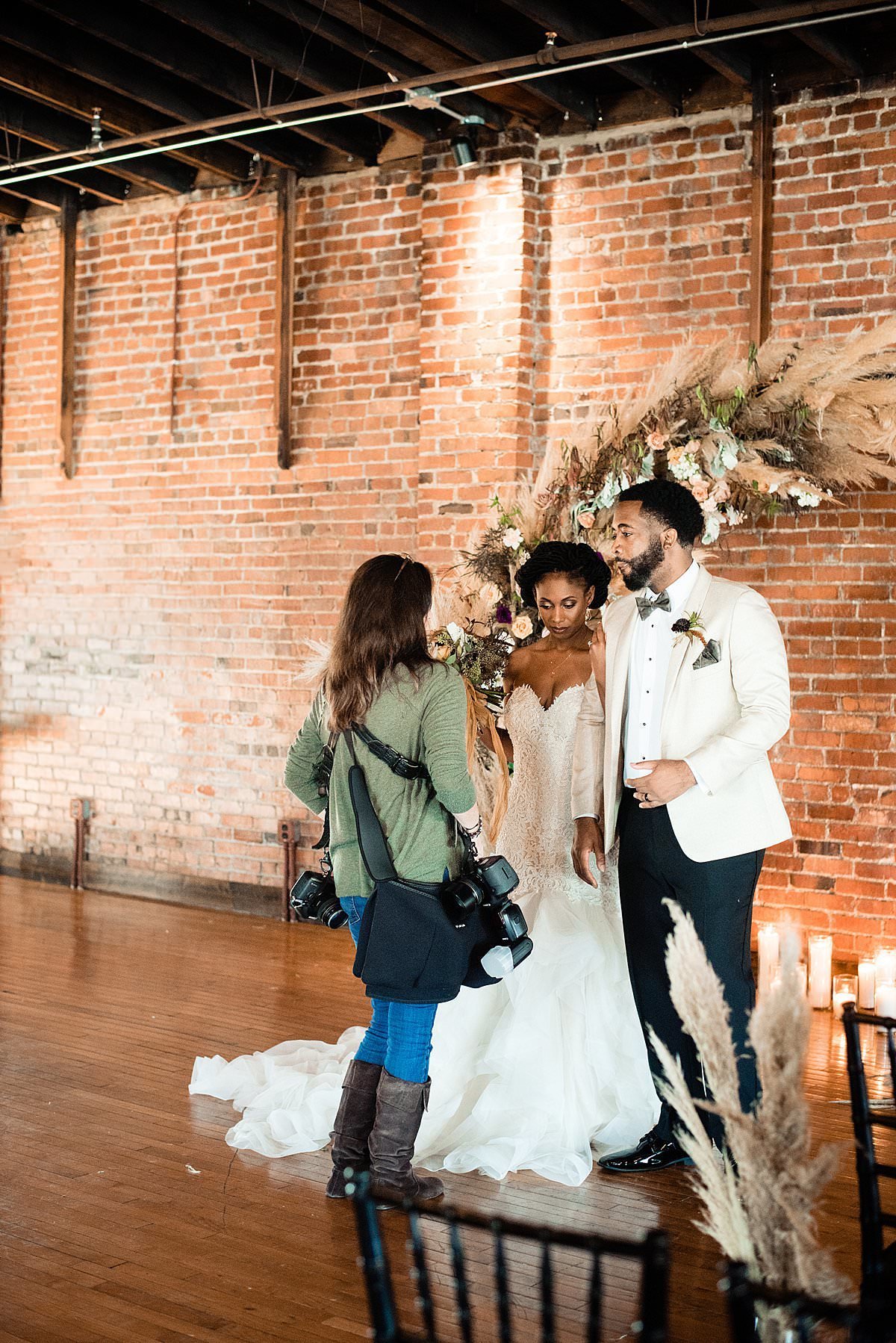 Photographer talking to bride and groom in front of their wedding arbor inside historic brick wedding venue in Nashville