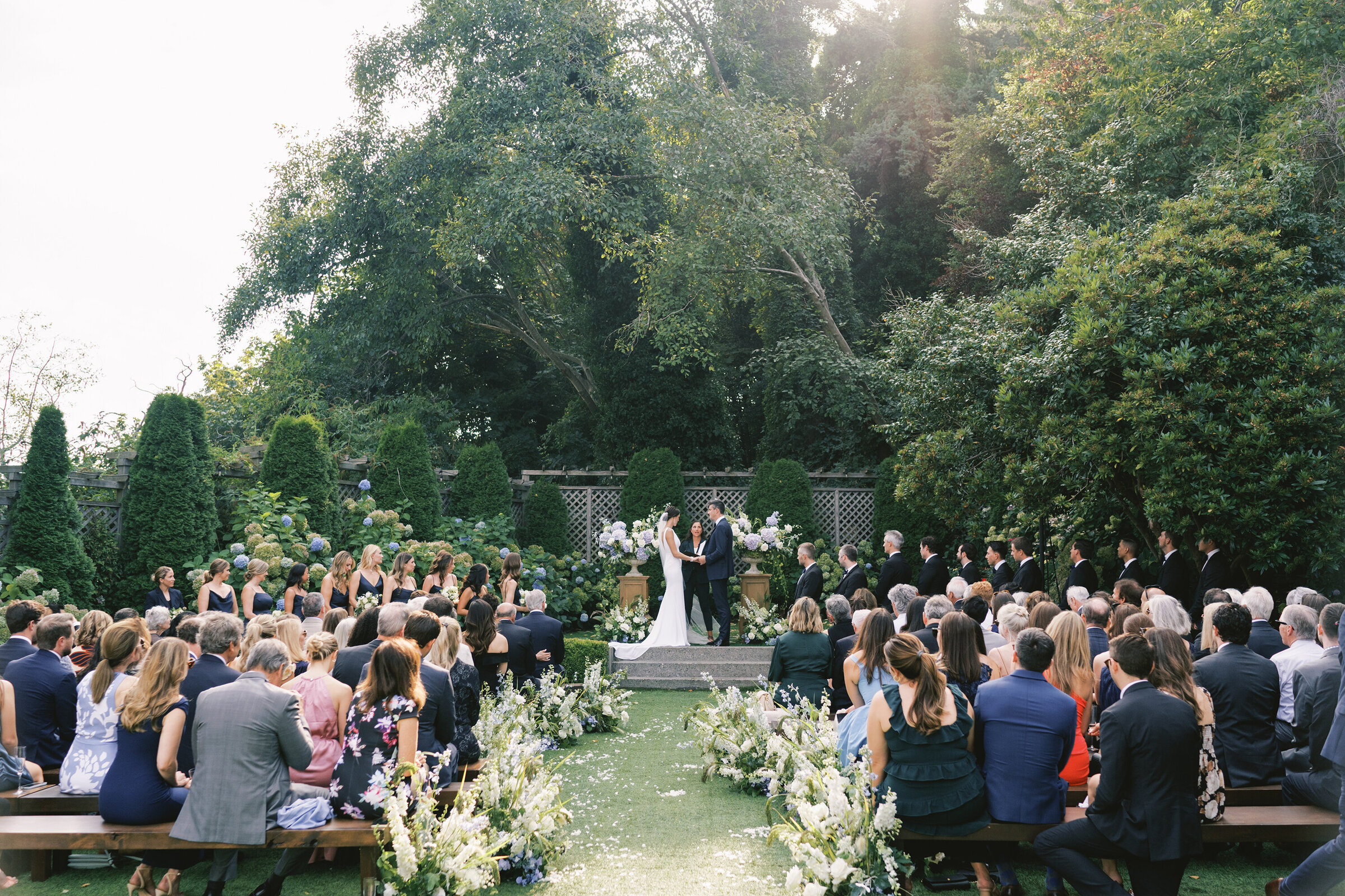 wide angle photo of wedding ceremony in green garden