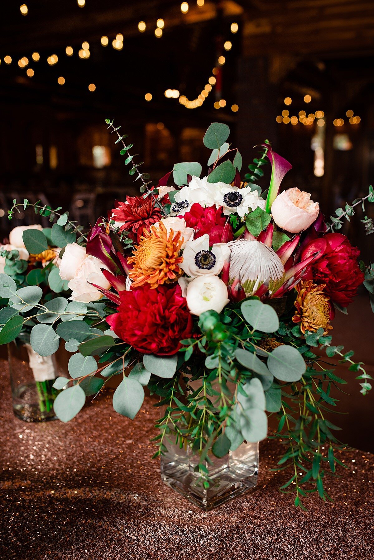 Large bride bouquet with protea, anemone, roses, birds of paradise, and other orange, red, and white flowers