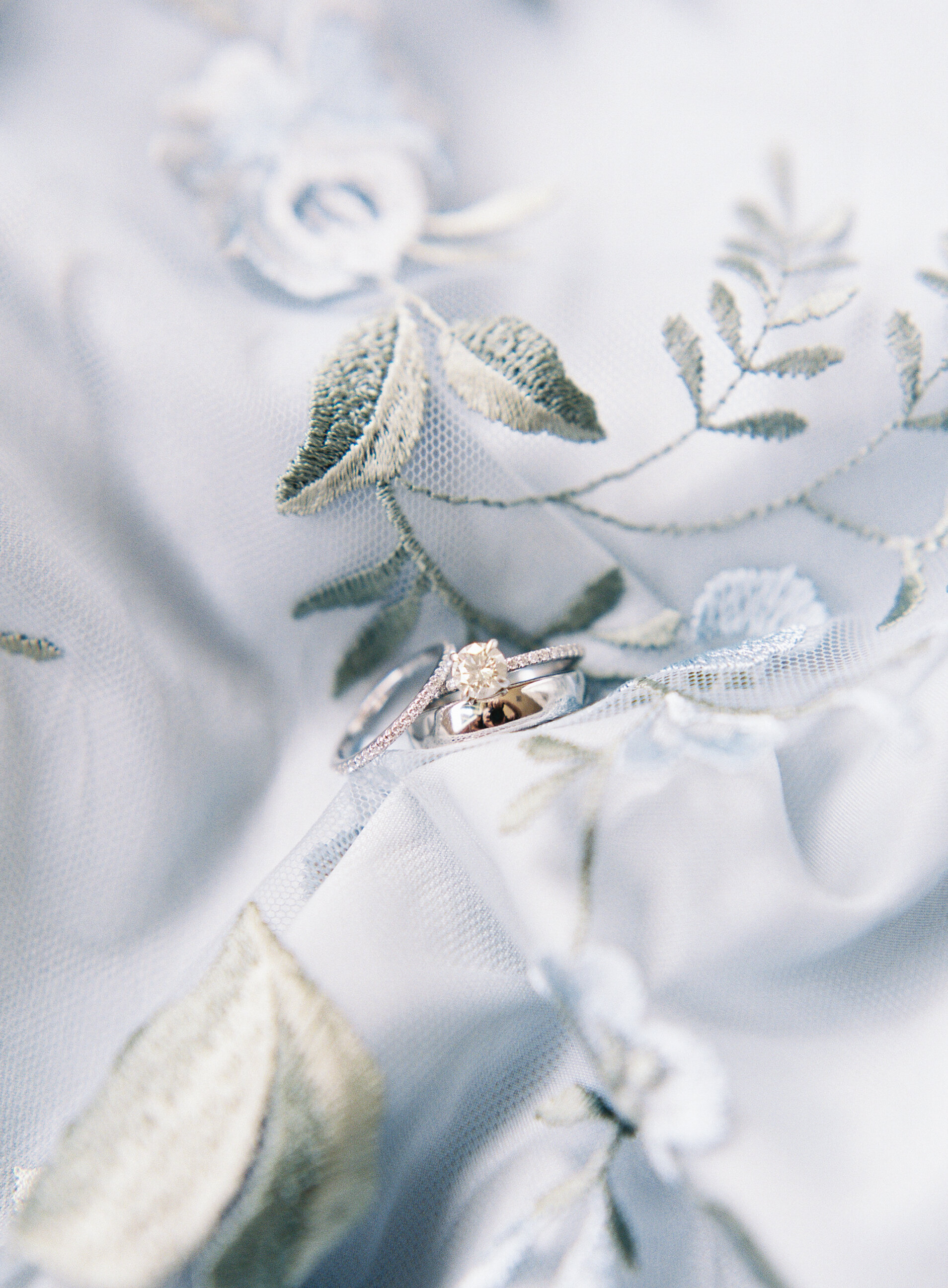 close up photo of diamond engagement ring on blue floral print fabric