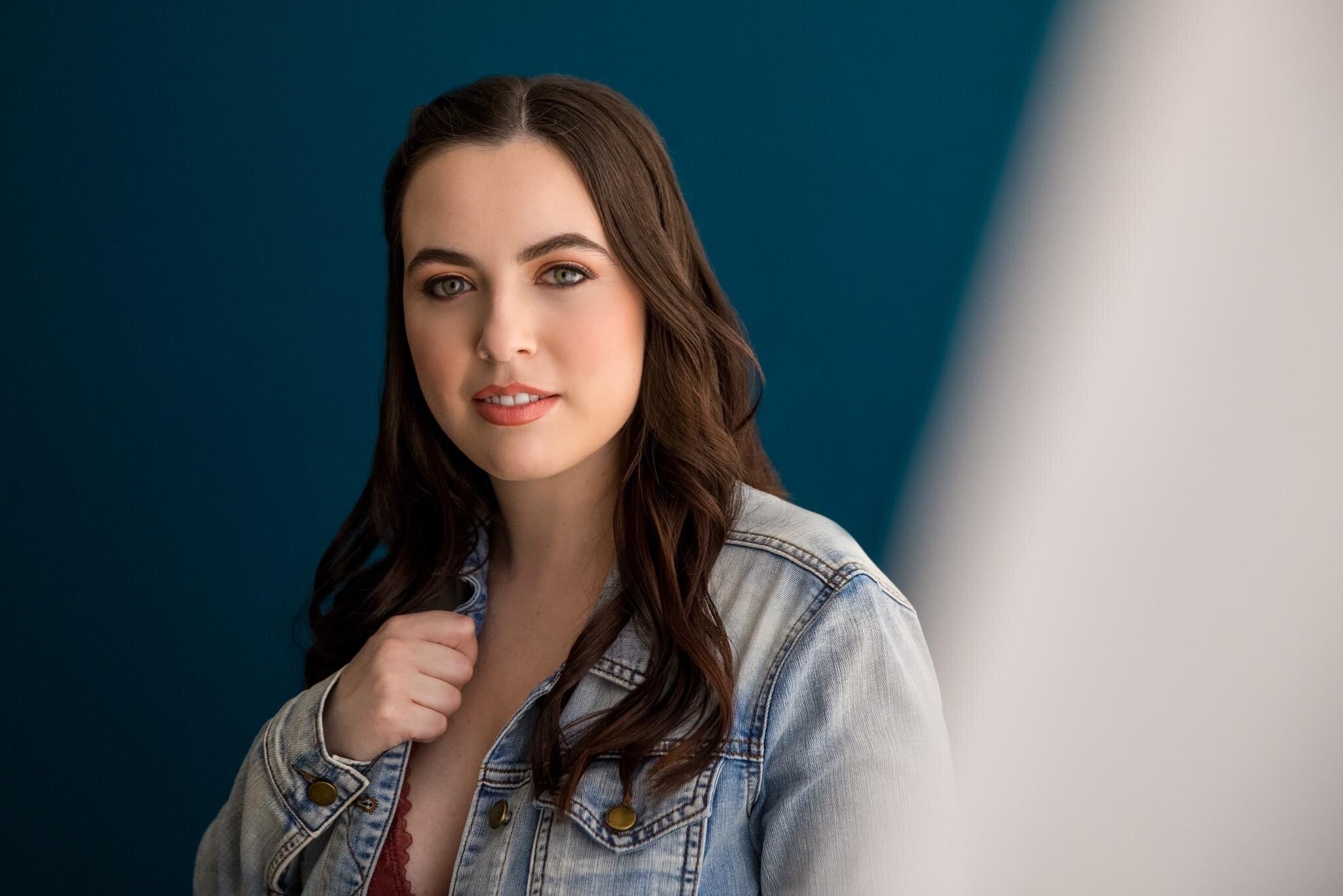 A profile of a woman with brown hair, wearing a jean jacket.