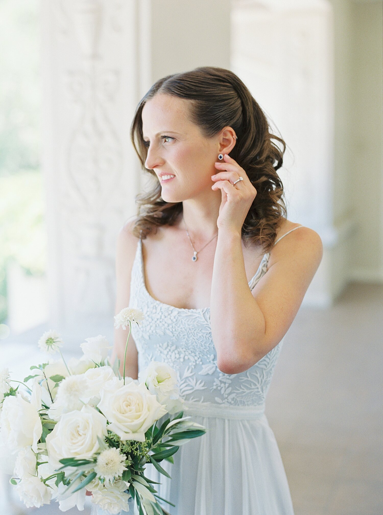 bride in blue dress tucks her brunette hair behind her ear