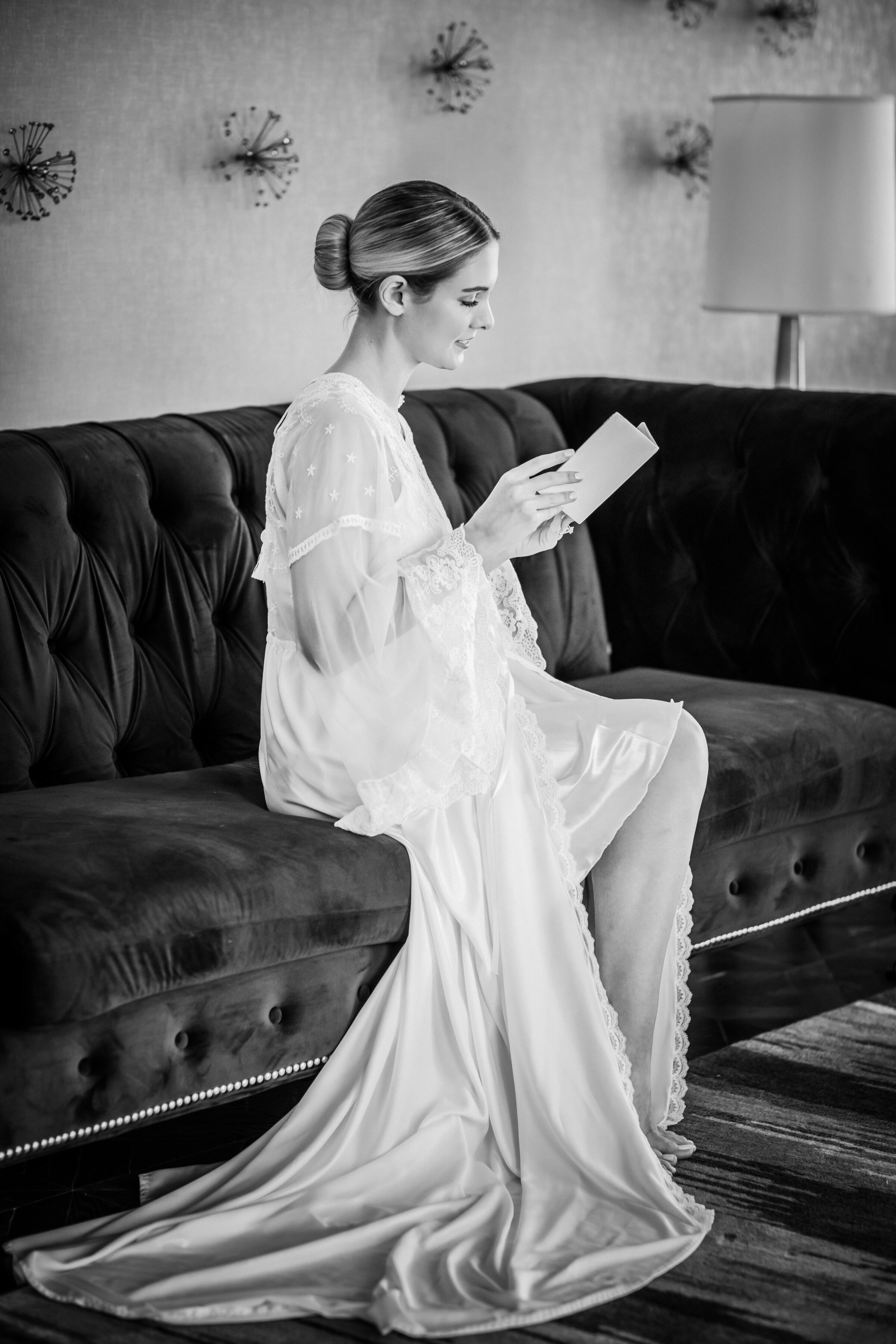 Bride wearing a maxi long sleeve bridal robe with a tight bun reading a letter from the groom at Bellevue Hotel in Philadelphia