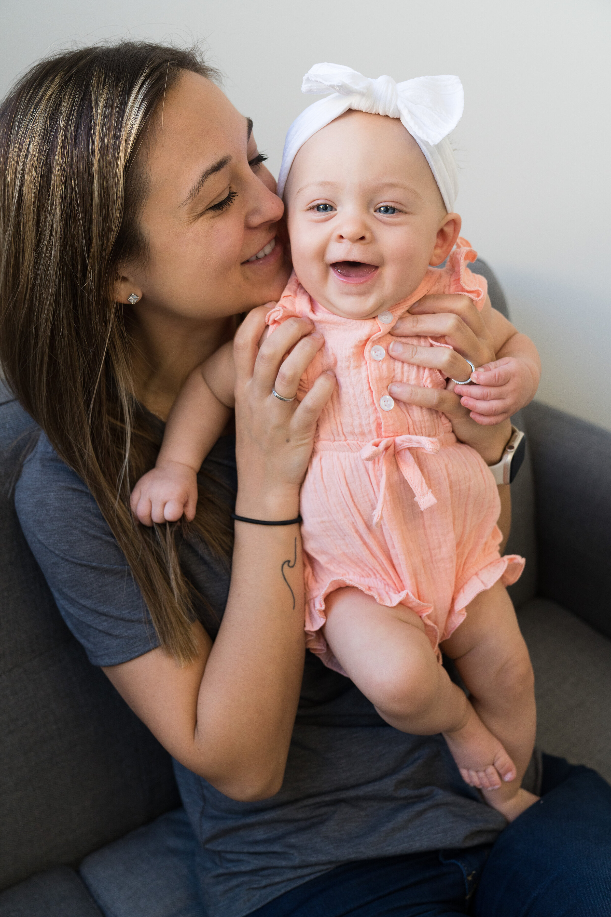 Mom gives kisses to her baby girl to make her giggle