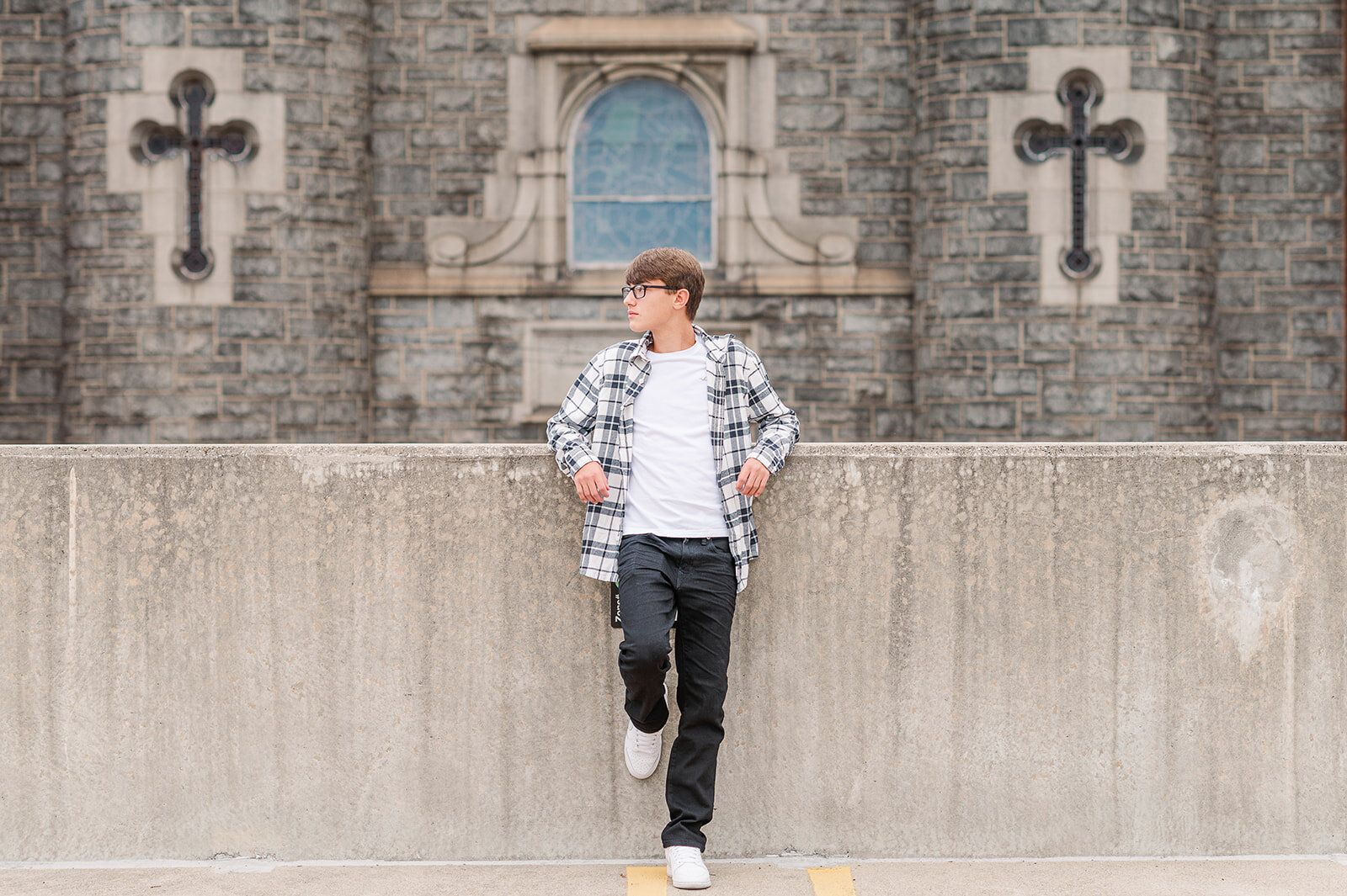 Senior boy standing on a rooftop ledge in front of a historic cathedral wall in downtown York, PA