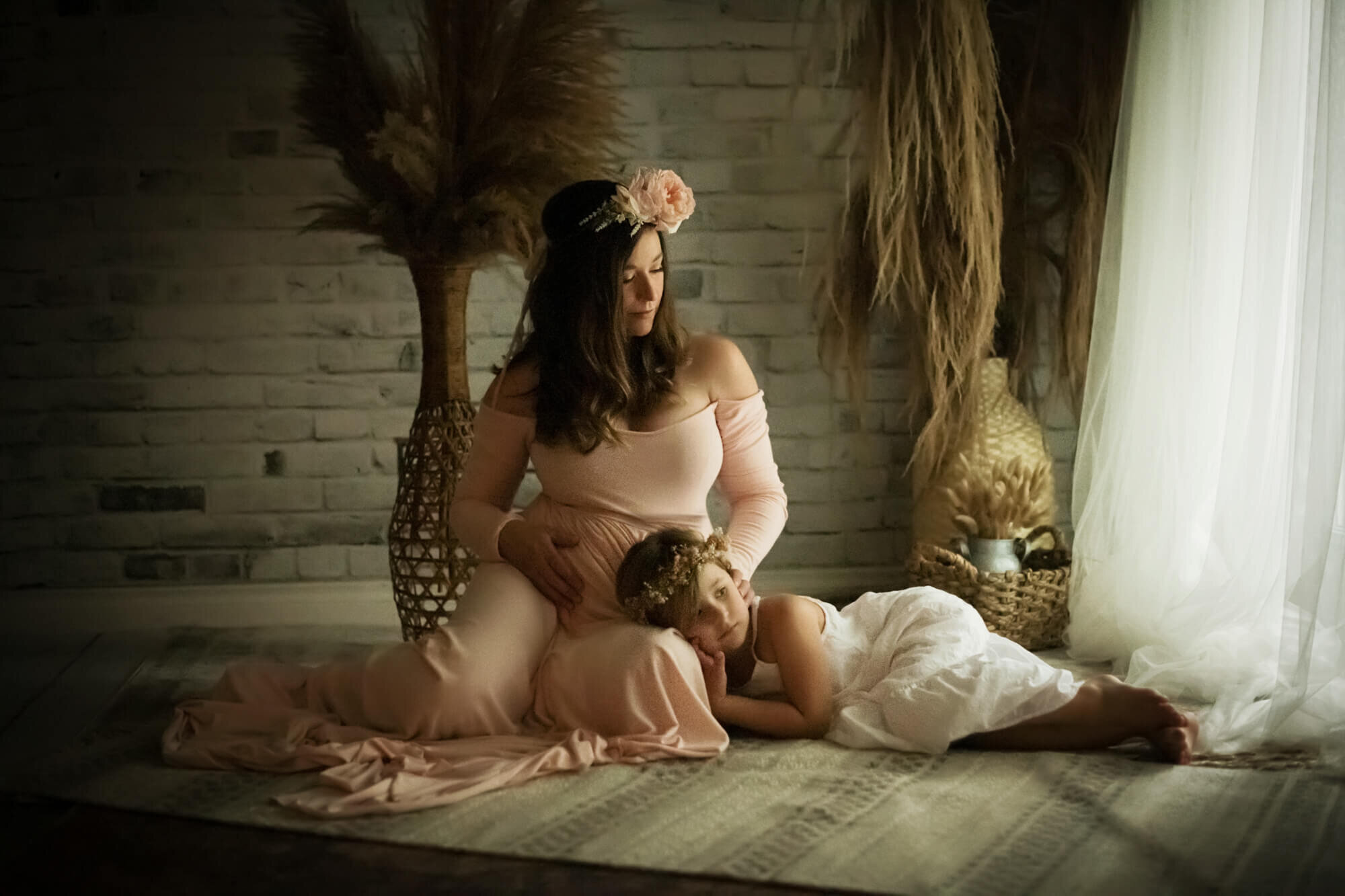 Expectant mother with daughter sitting gazing out window