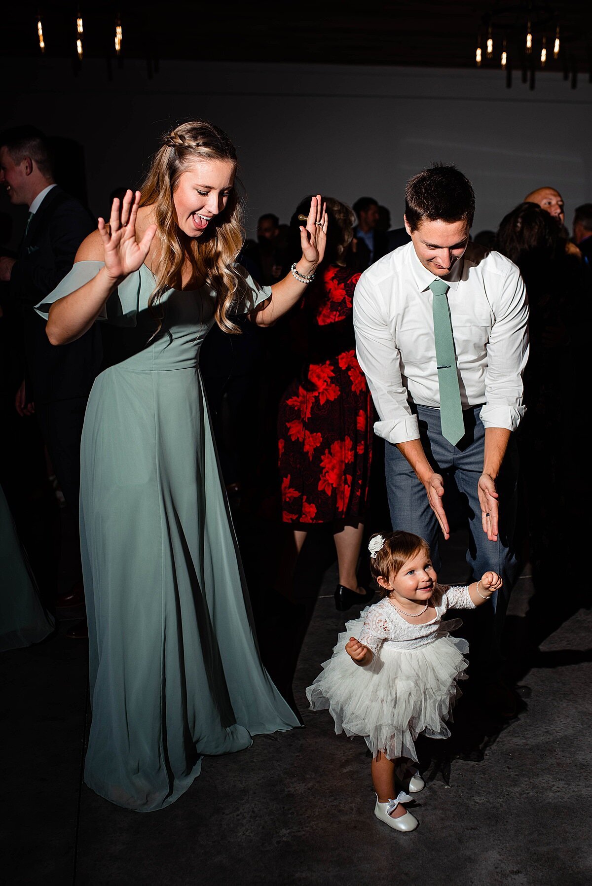 Flowergirl wearing tulle skirt dancing with her mom and dad on the dance floor at Cranford Hollow