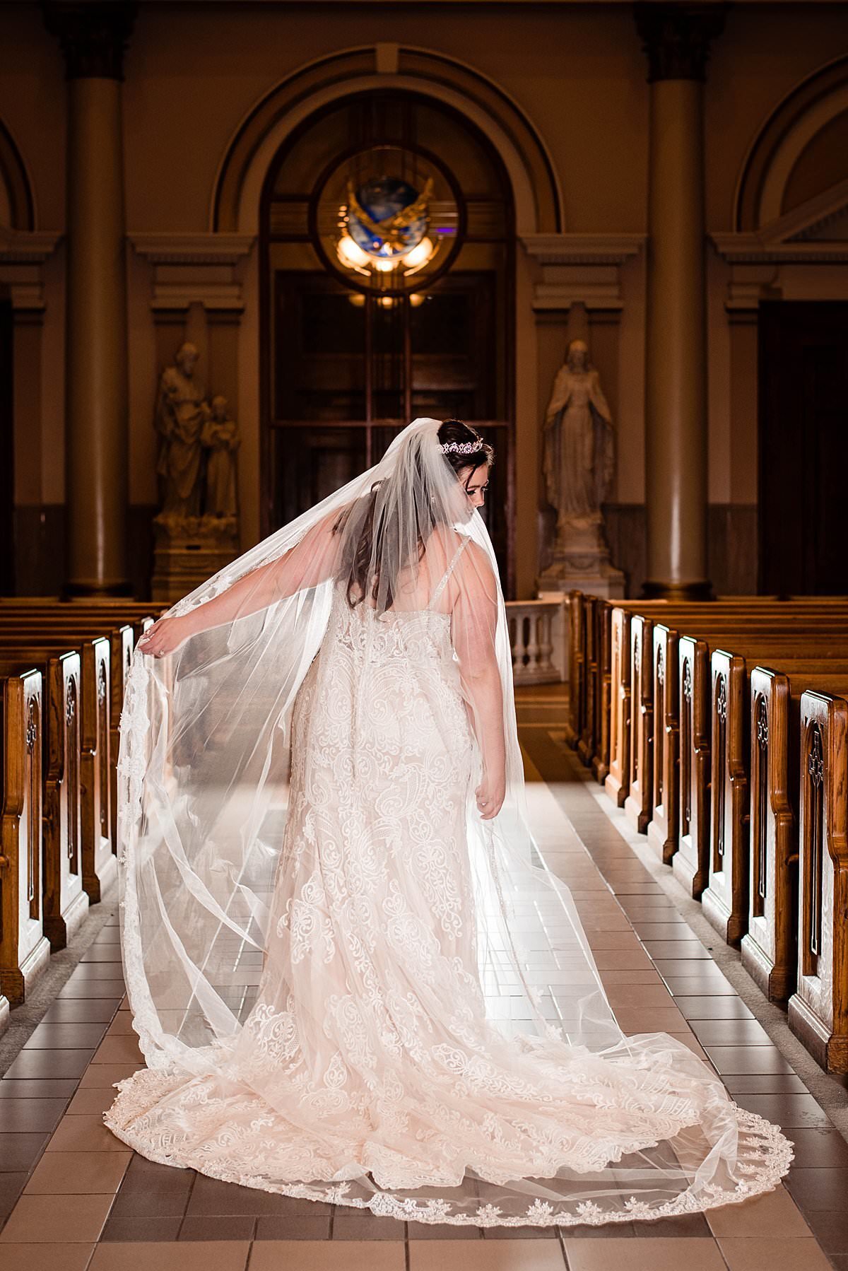 Bride standing in aisle at cathedral of incarnation with her cathedral veil behind her
