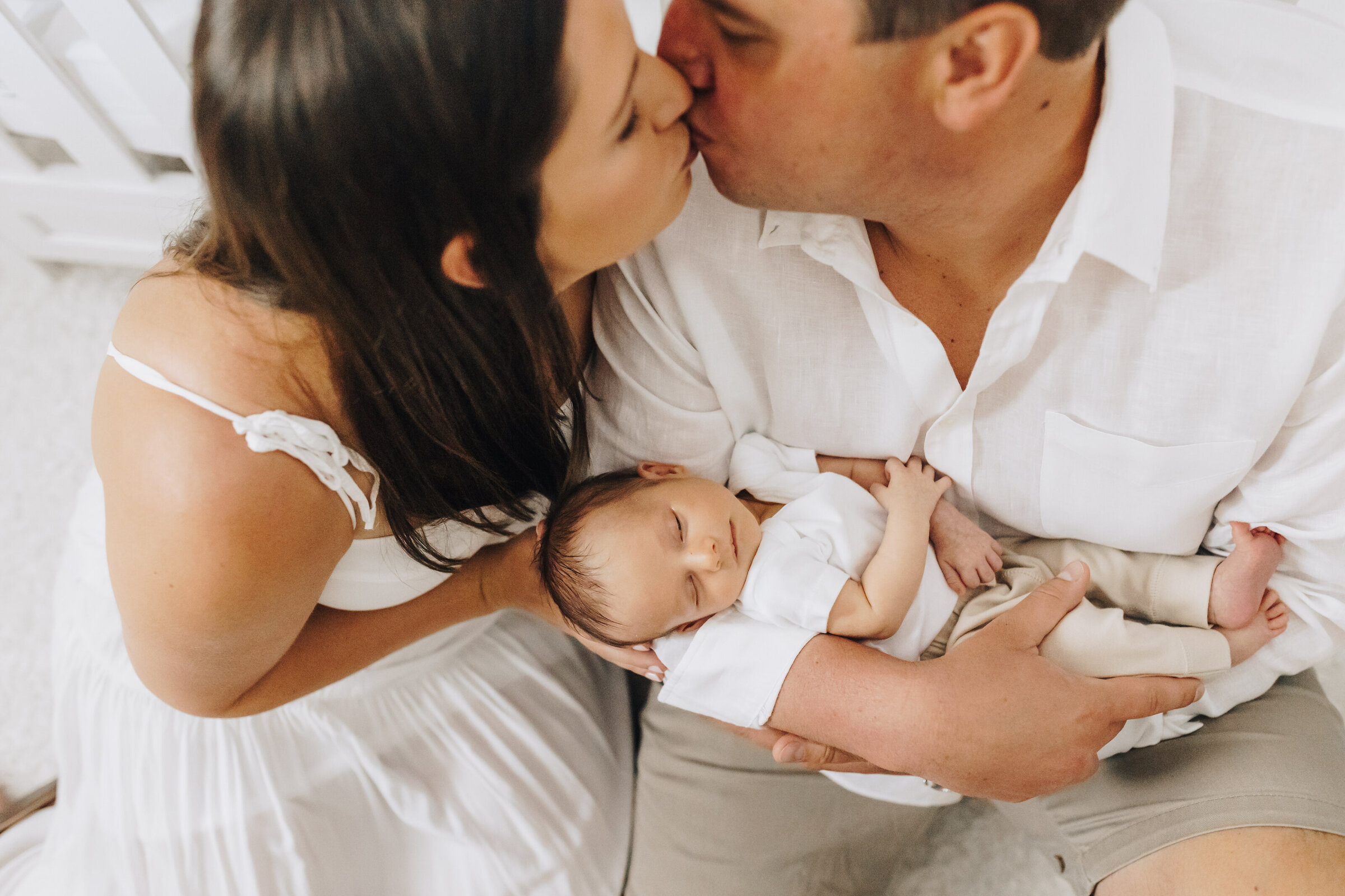 Mom and Dad Kiss Holding Newborn