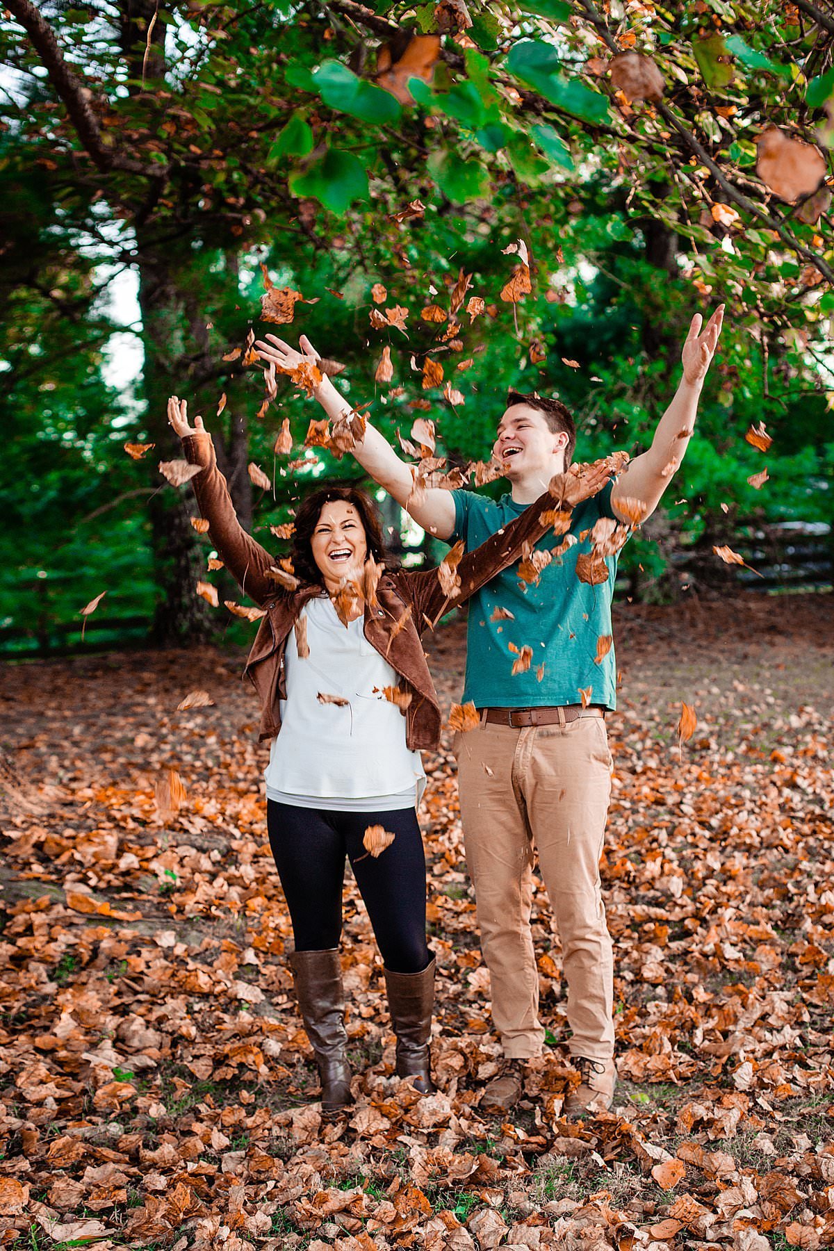 Engaged couple tossing leaves into the air in celebration