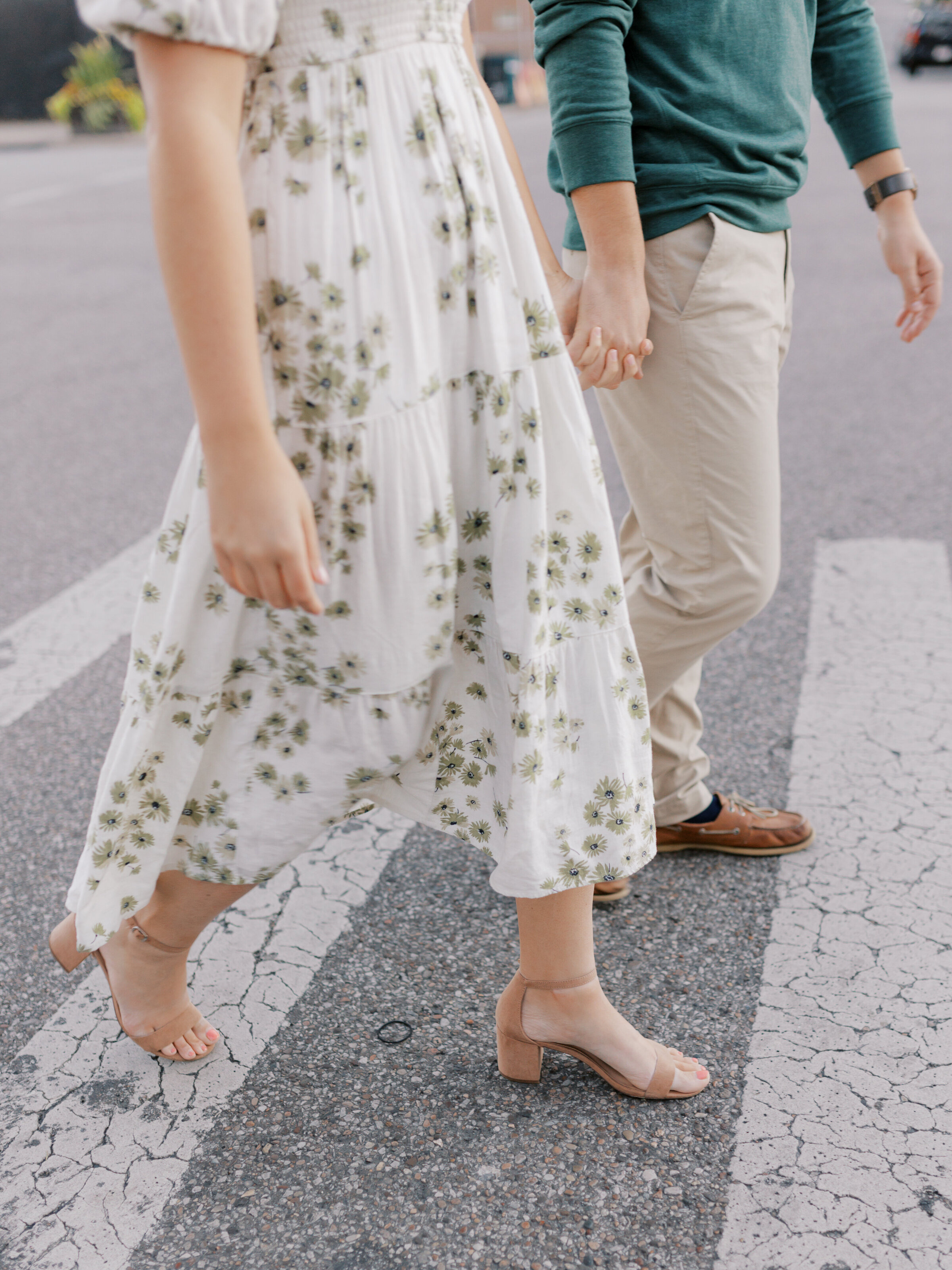 A couple holds hands and walks across the street during their downtown Cincinnati engagement session.