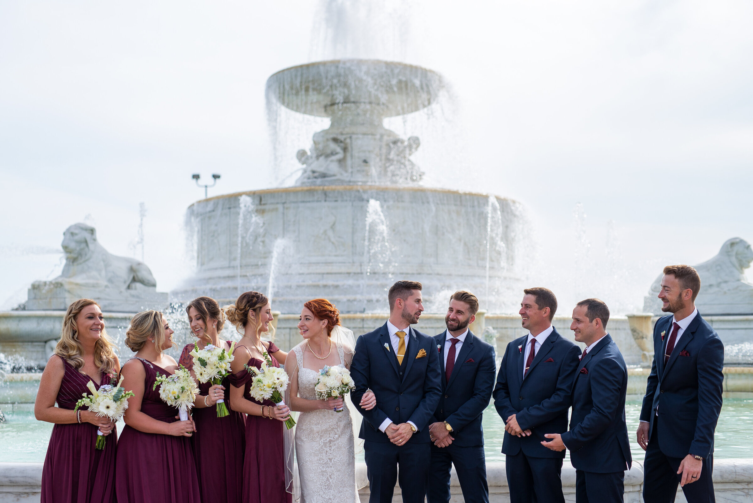 Wedding party standing and laughing in front of the Belle Isle fountain, in Detroit Michigan.