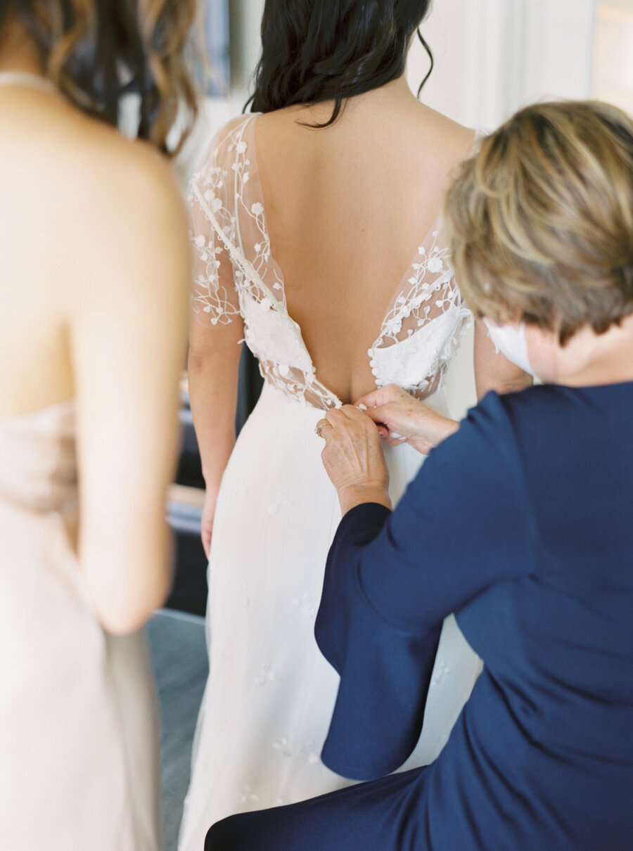 mother of the bride in navy dress buttons up the brides wedding dress