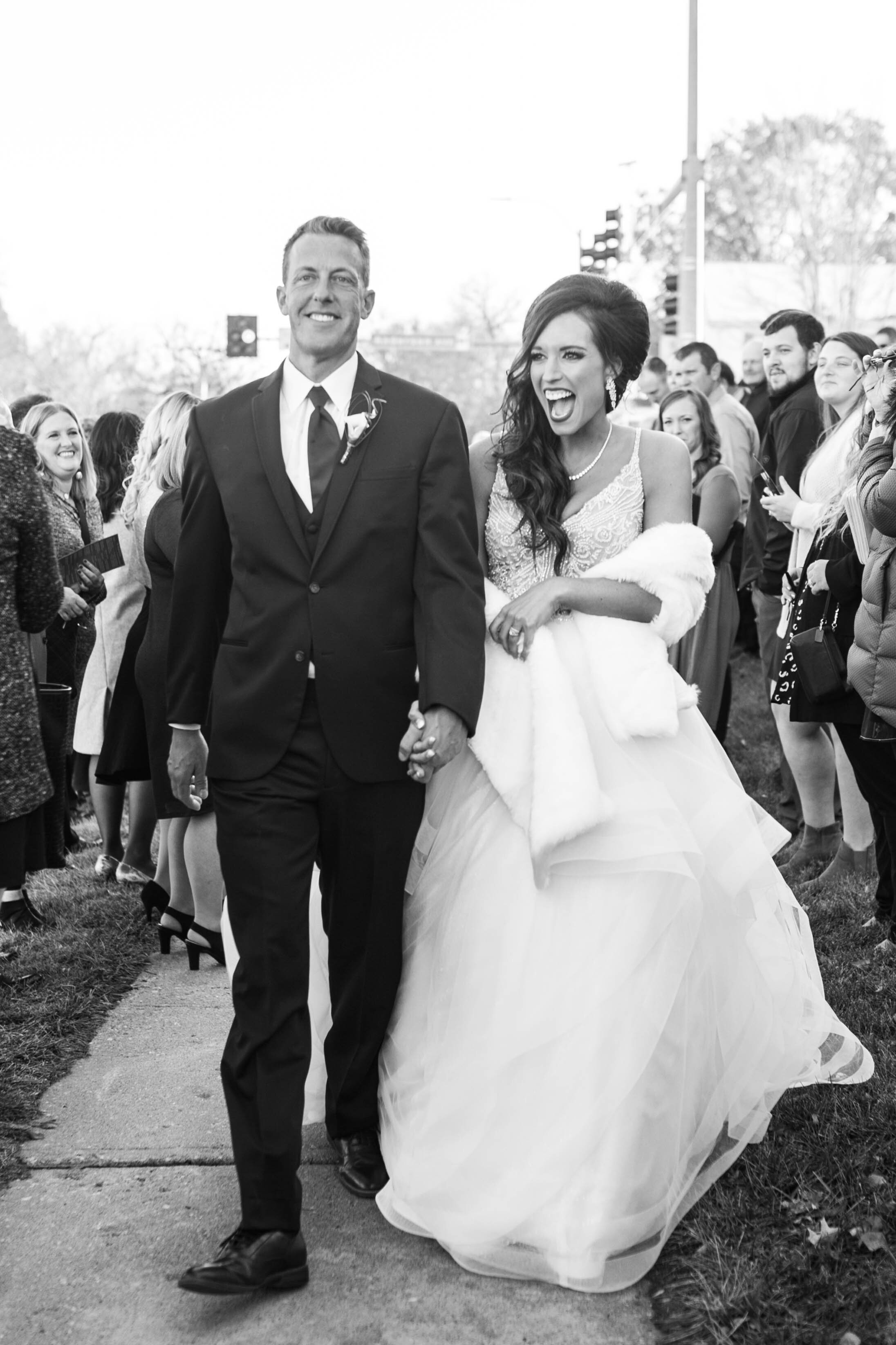 Bride and groom leaving the ceremony, surrounded by cheering family and friends.