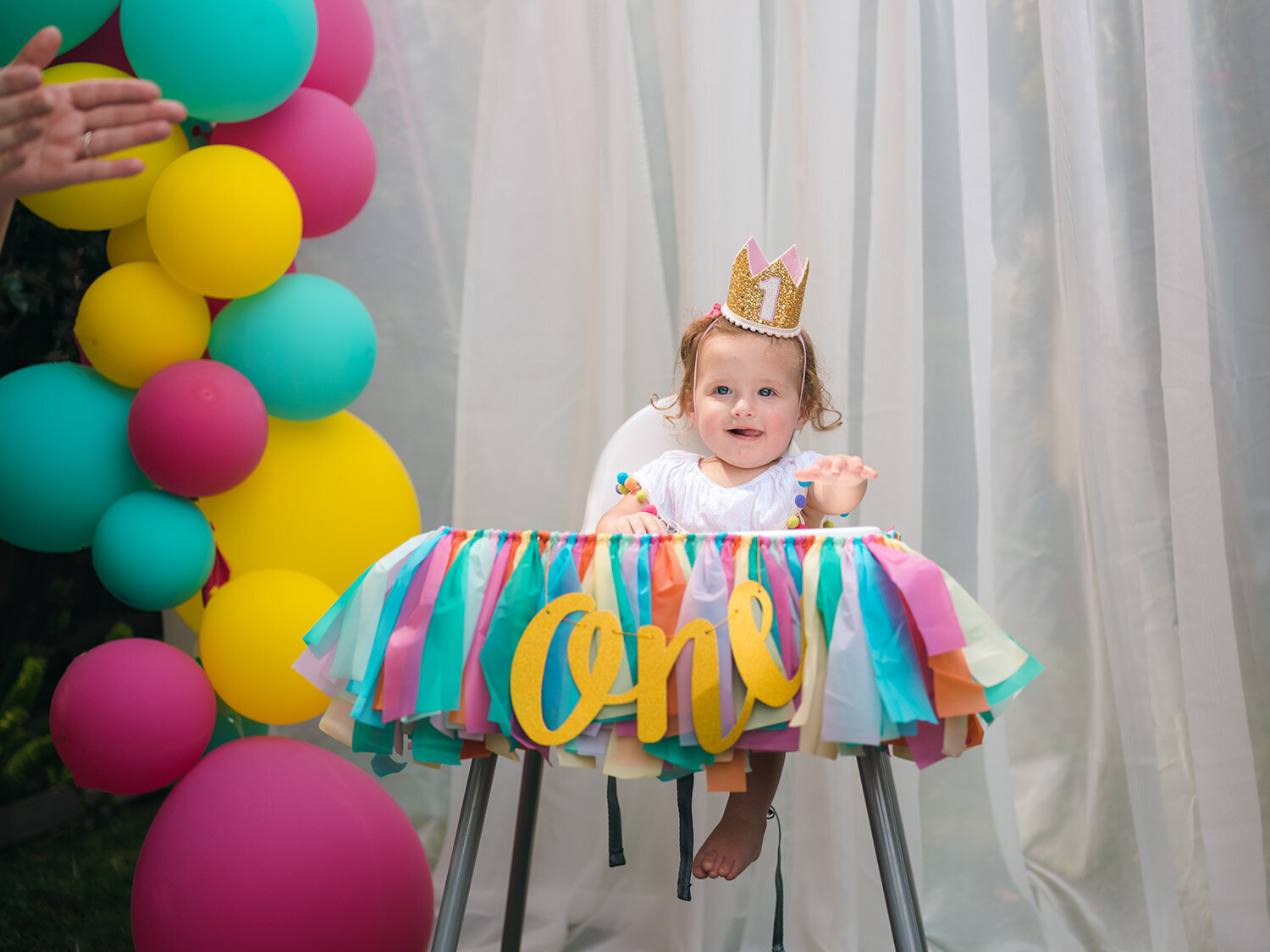 Baby smiling and clapping during her first birthday party as guests sing Happy Birthday in San Francisco and the Bay Area