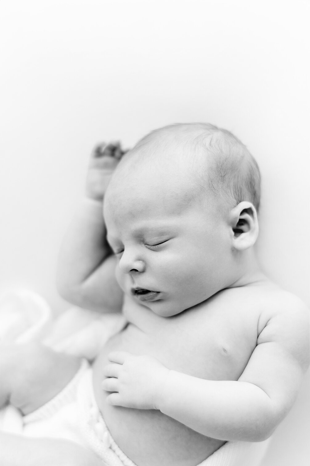 black and white image of a sleeping newborn with arms raised  in Kristie Lloyd's Nashville newborn photography studio