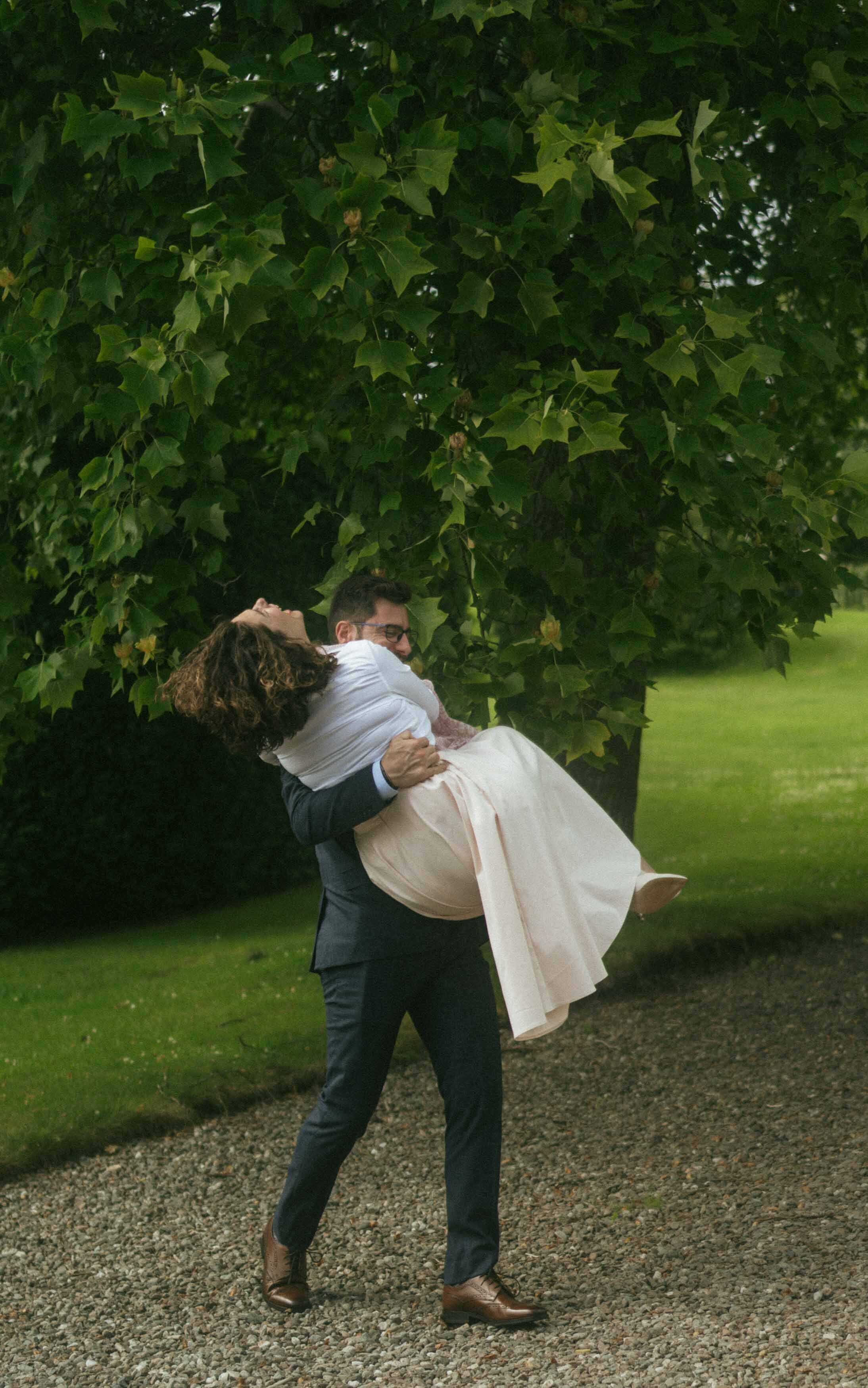 A heartfelt moment as a fiancé carries his future wife in his arms, capturing their love and excitement before their wedding day