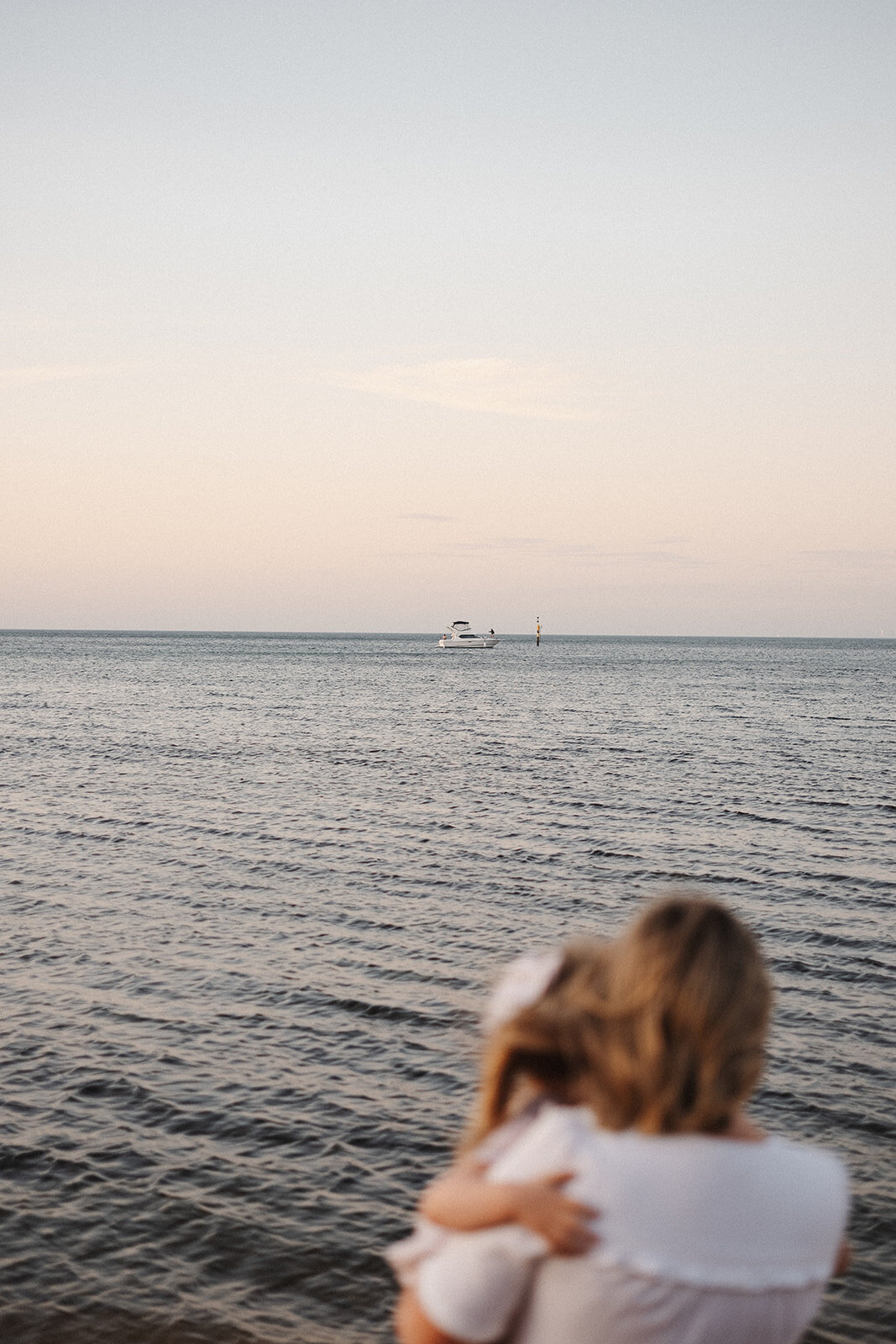 mum holding daughter watching the waves