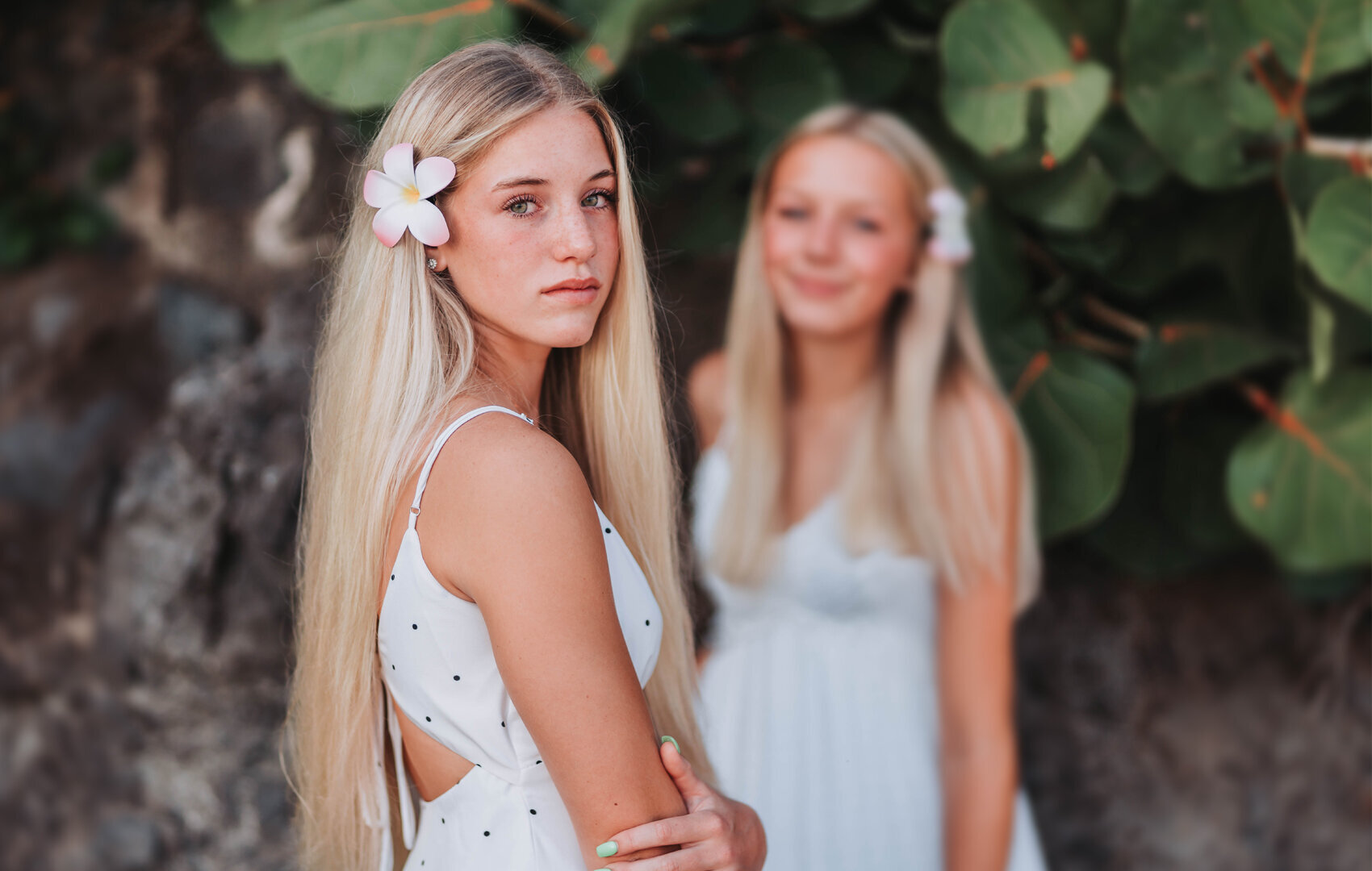 Graduation pictures for two all in white with pretty flowers in their hair.