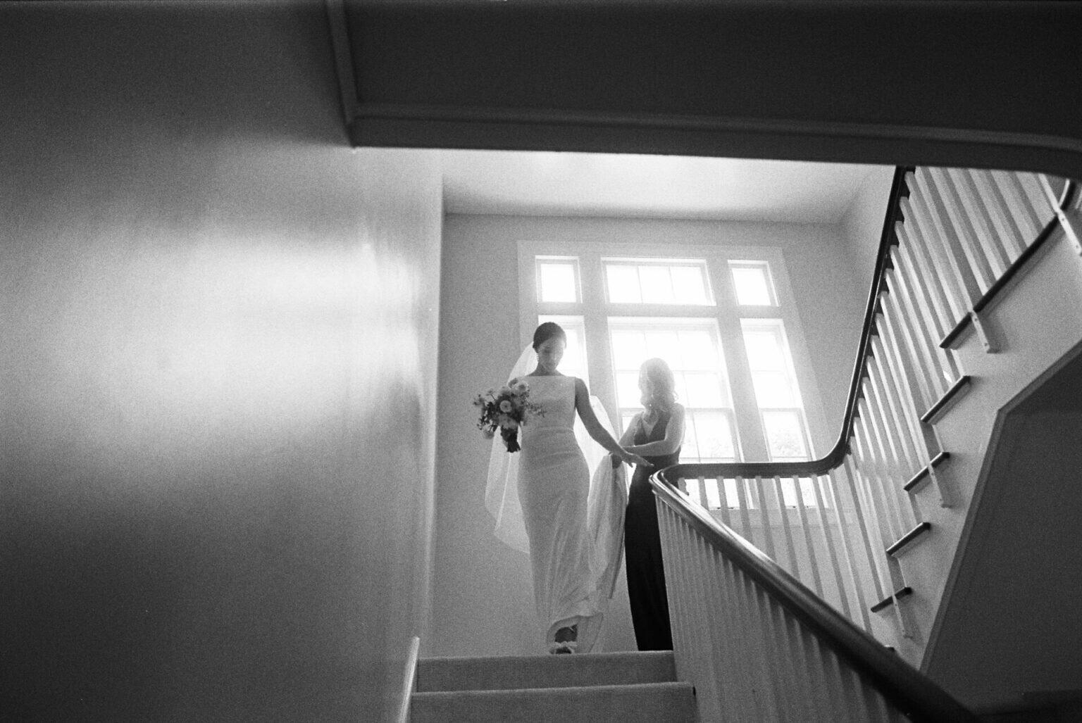 black and white photo on film of bride walking down stairs