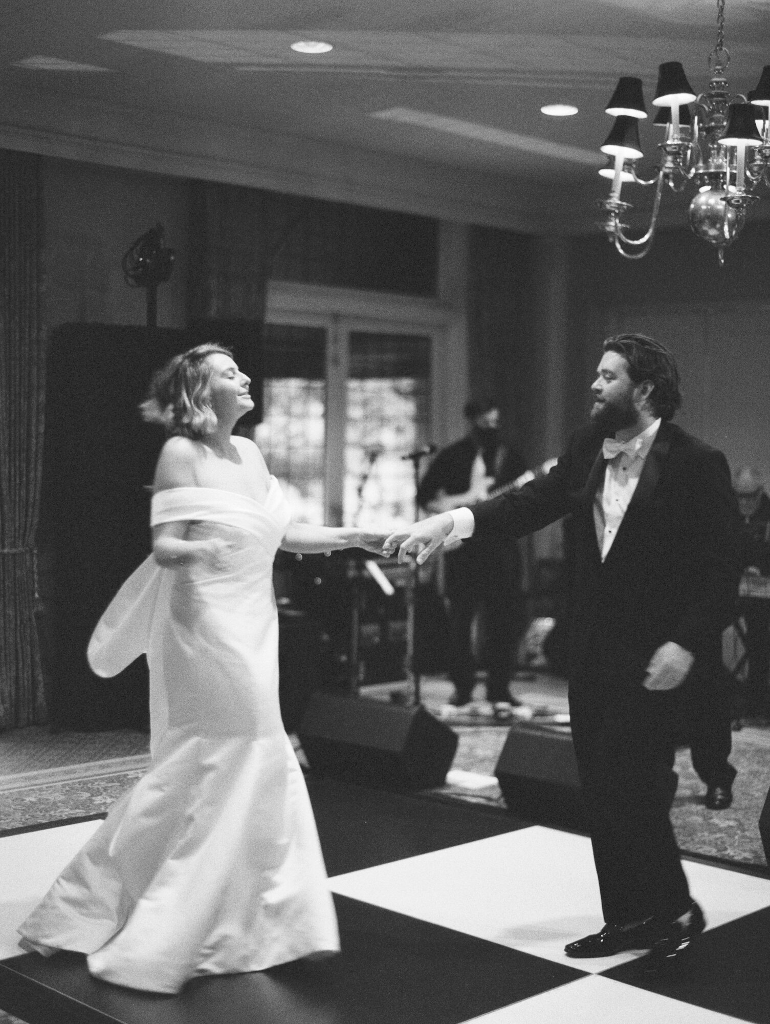 bride dances with groom on checkerboard dance floor black and white