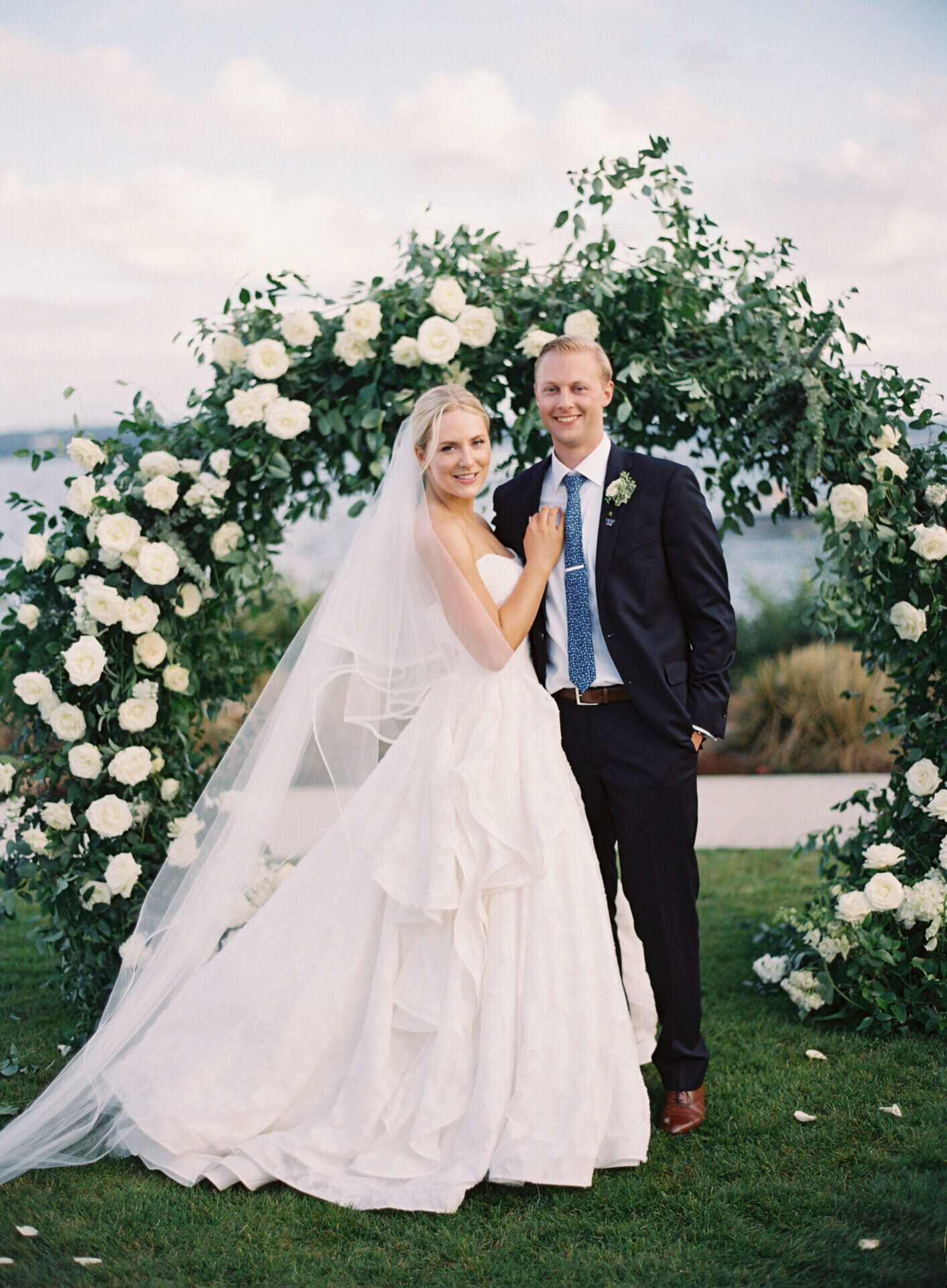 film portrait of bride and groom at the seattle tennis club in front of floral arch of roses