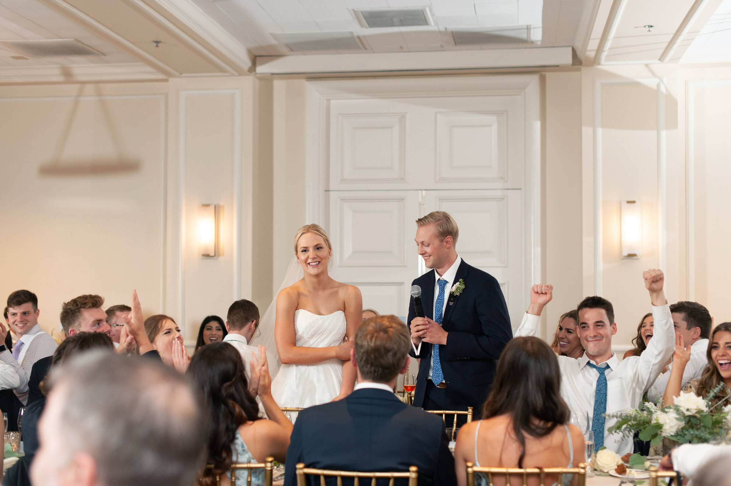 bride and groom laughing while giving speech in ballroom reception
