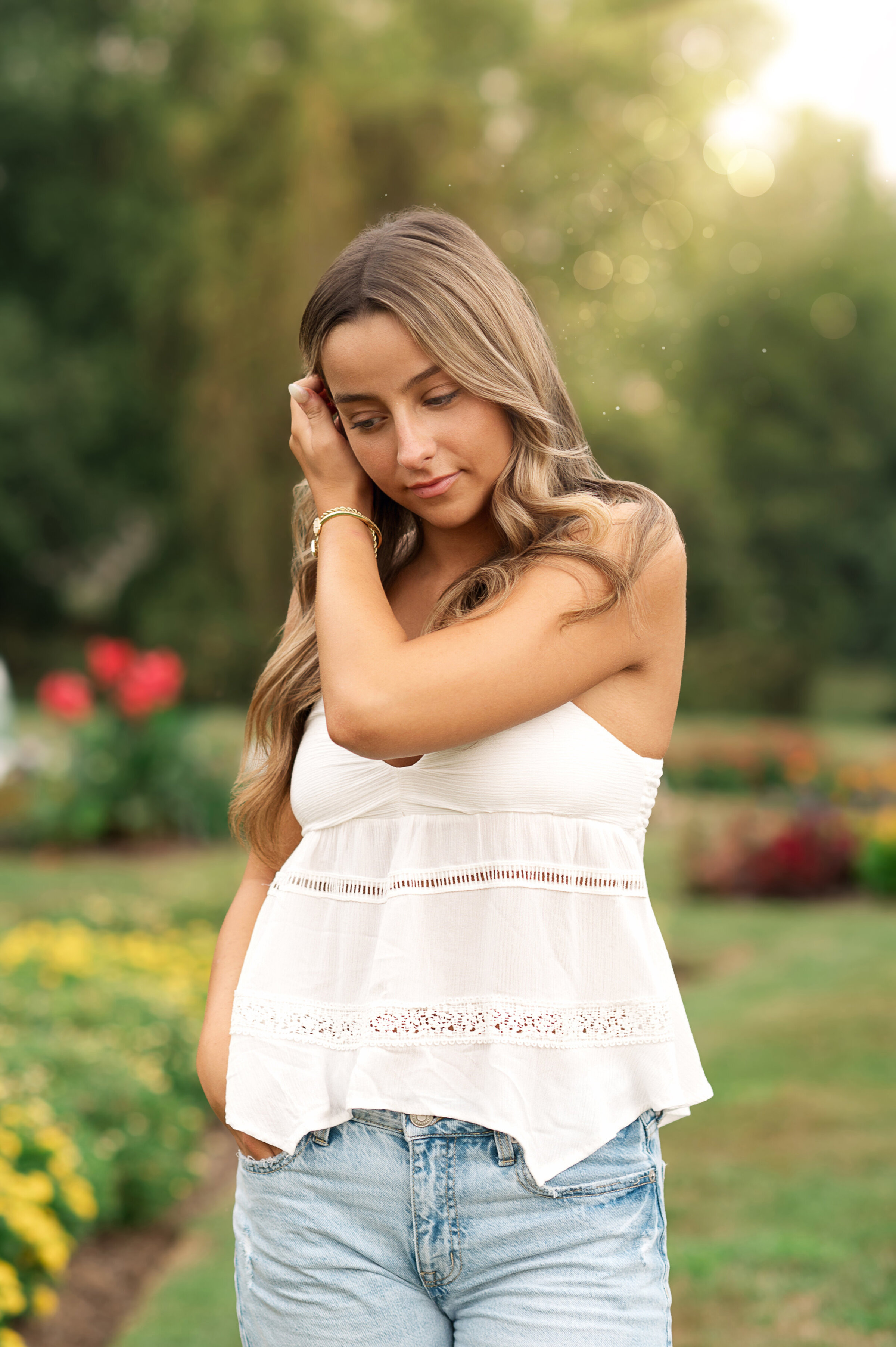  Senior girl in a white tiered dress posing in lush green garden at Hershey Gardens near York, Harrisburg, and Lancaster PA.

