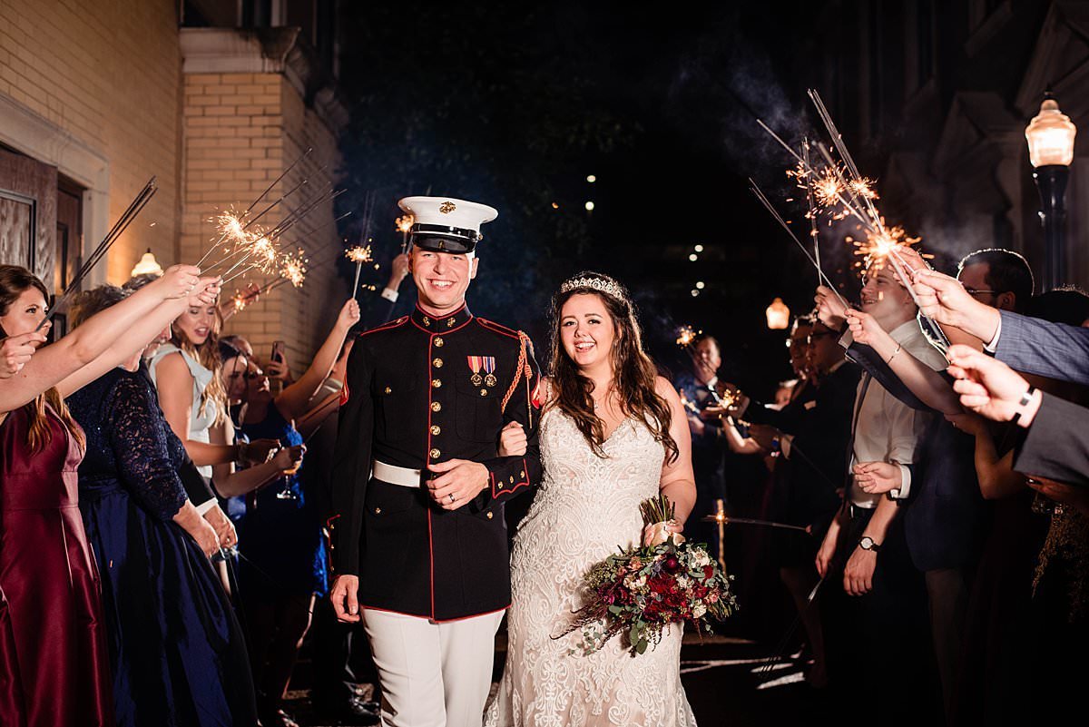 Marine escorting his wife through sparklers for their wedding reception exit