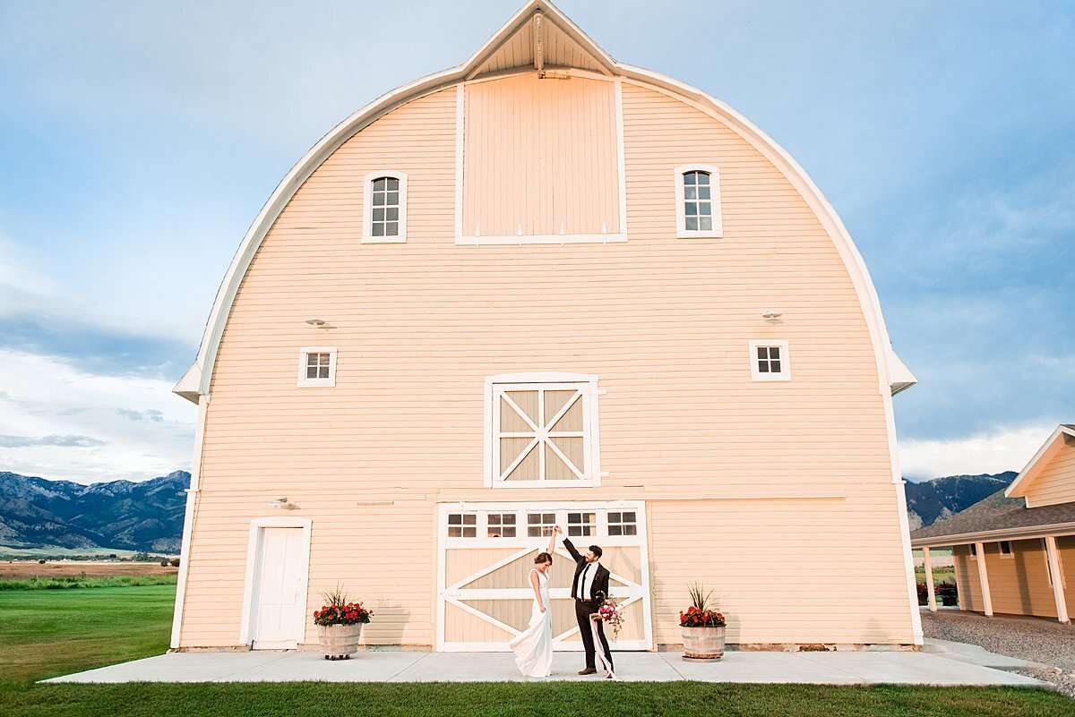 Bride and groom dancing together in front of the Big Yellow Barn outside Bozeman Montana